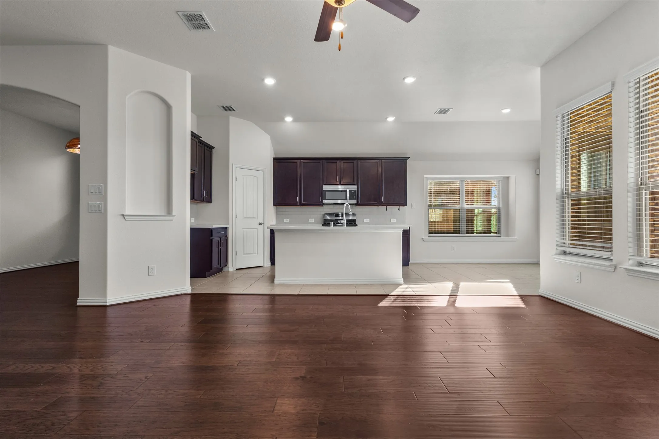 Open concept living space featuring recessed lighting, dark wood-finish flooring, a ceiling fan, and large windows with blinds