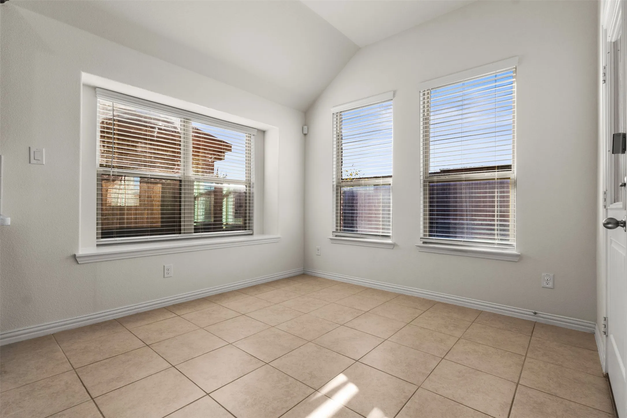 Tile flooring, multiple windows, vaulted ceiling, white walls, white trim