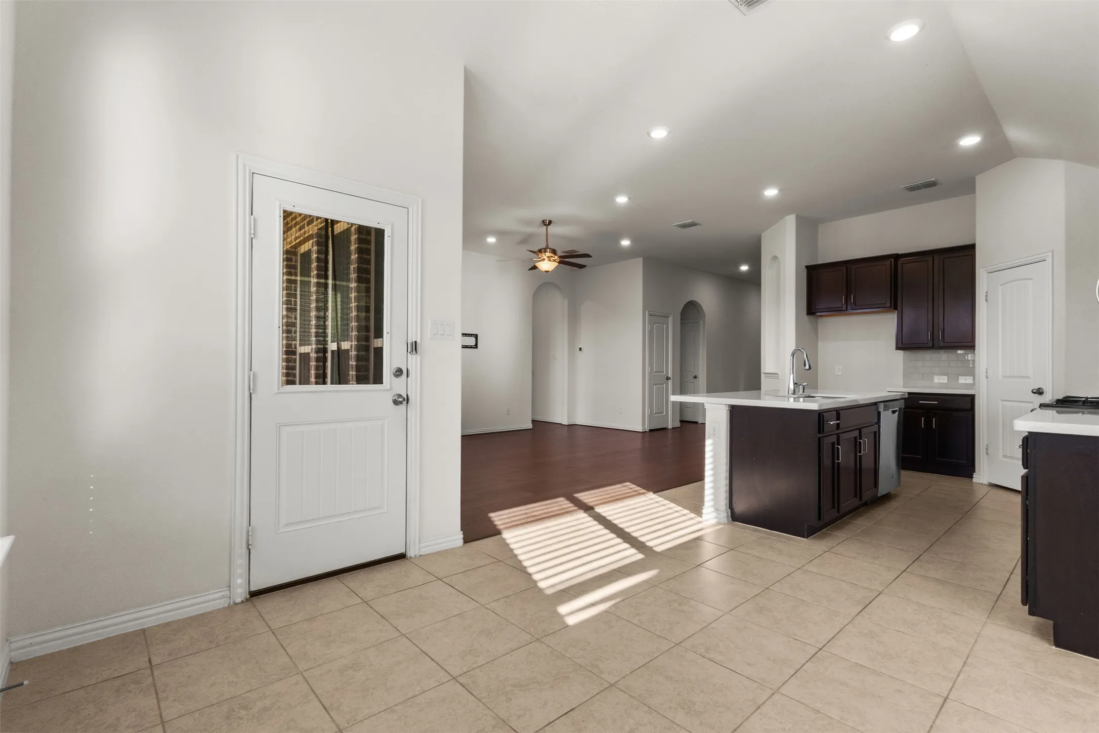 Kitchen featuring tile flooring, a center island with sink, dark wood-finish cabinetry, and recessed lighting