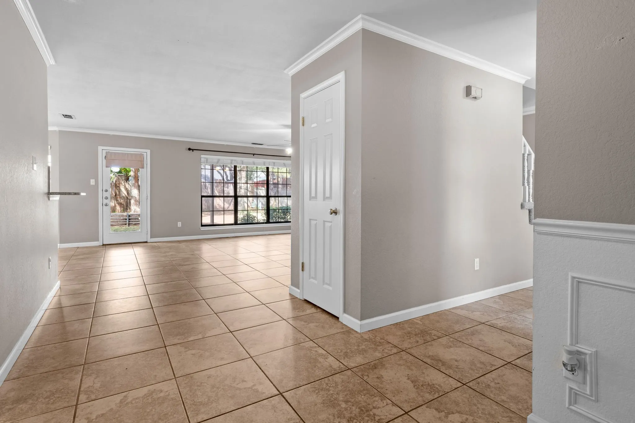 Entry view to the living room and stairway up to the second floor with coat closet underneath. Hallway to right offers a half bath, laundry room and leads to the side entry two car garage plus access to the stairway to upper level.