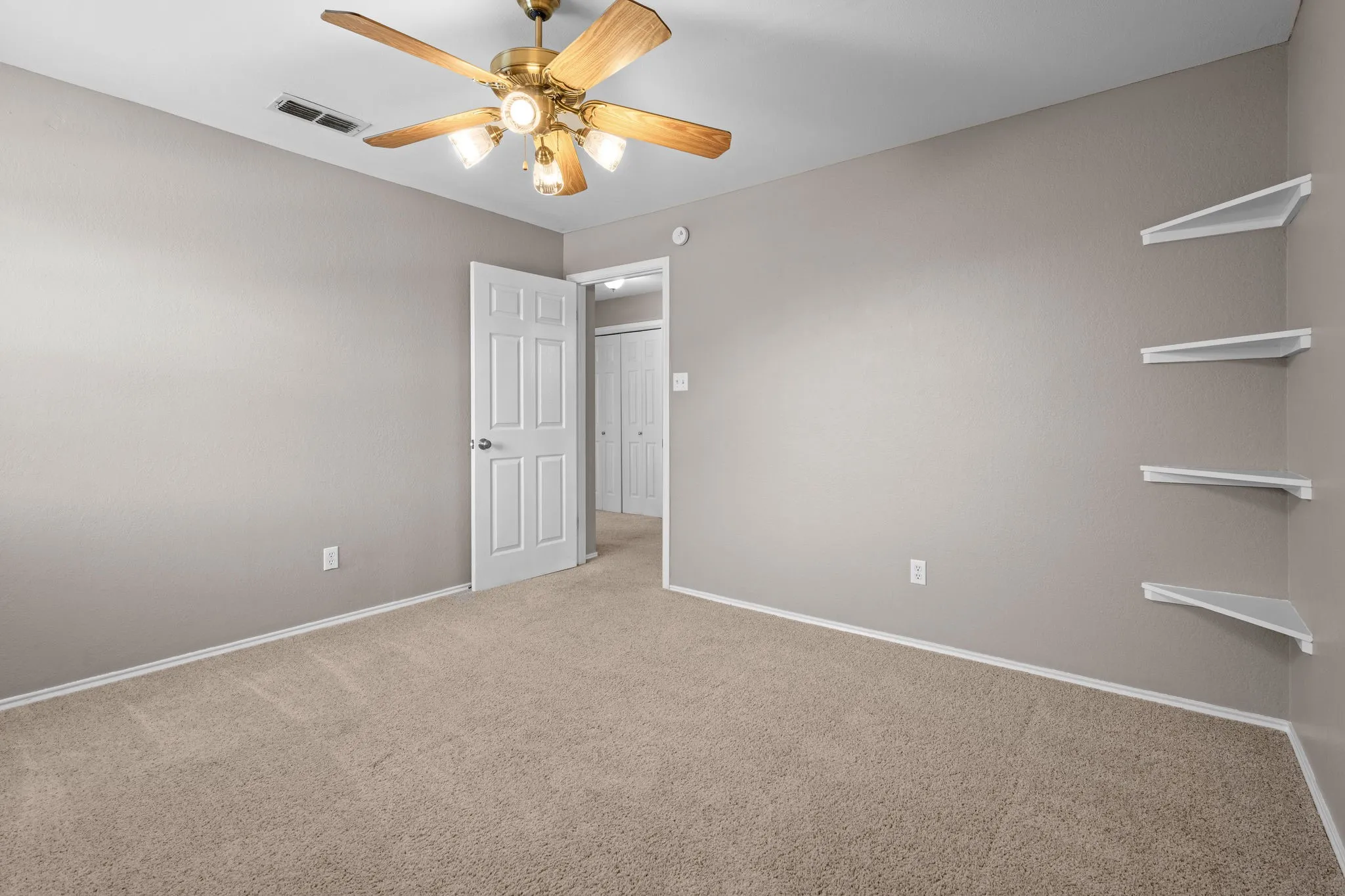 Middle bedroom with ceiling fan and built in corner shelving.
