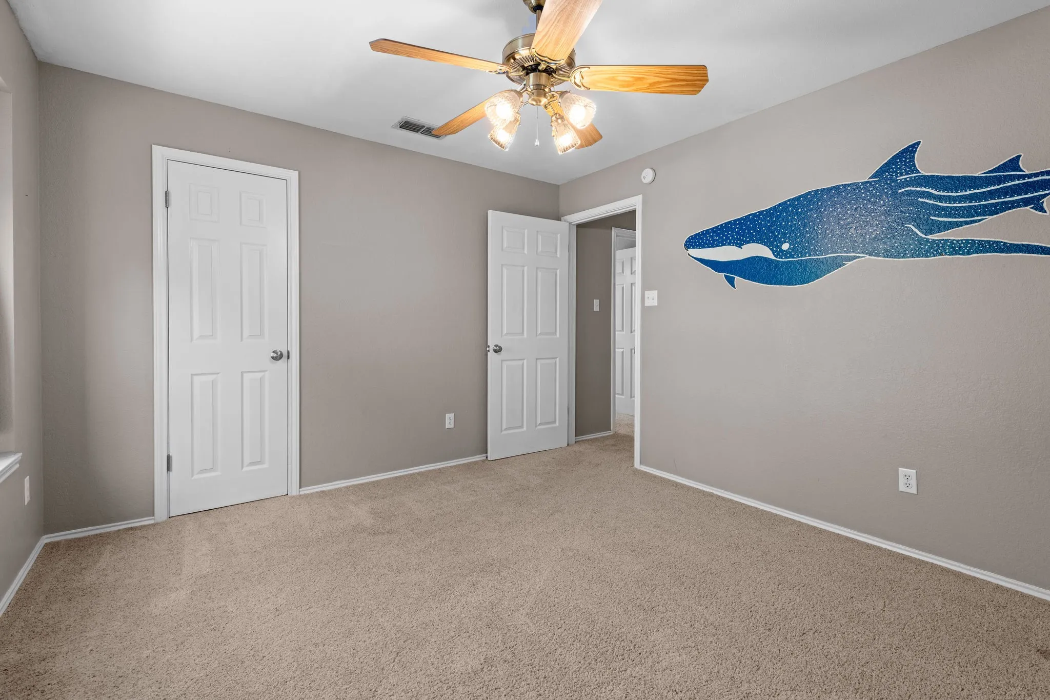 Back bedroom with whale wall art, ceiling fan and closet.