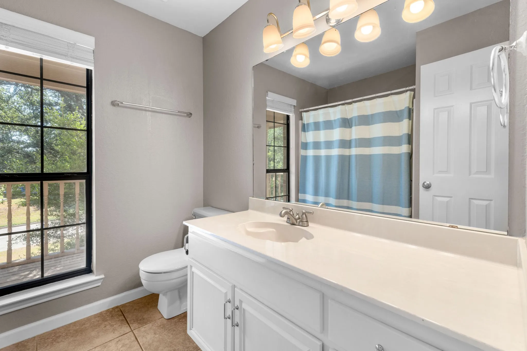 Full bathroom upstairs with single sink and window view to upstairs balcony.