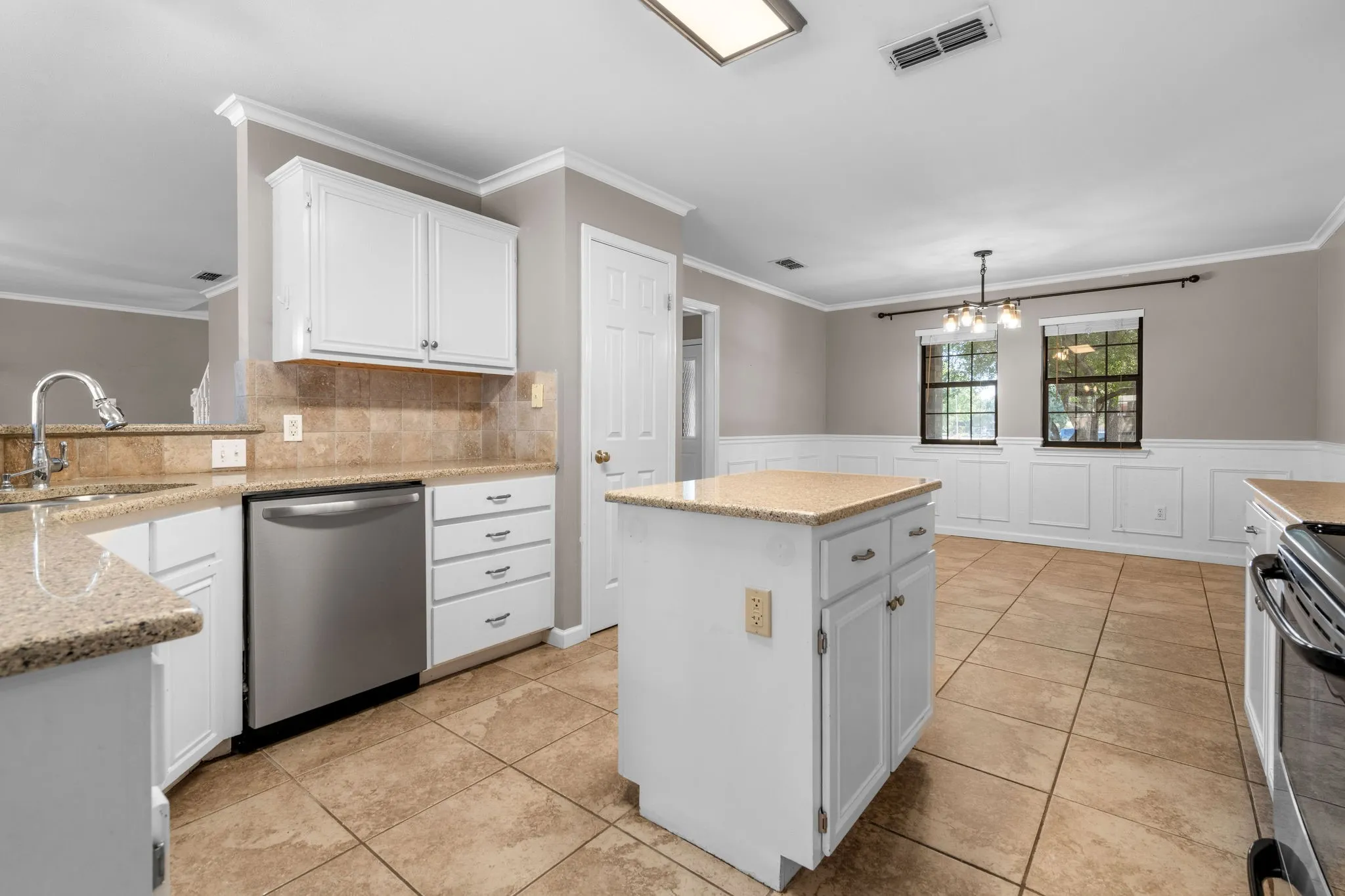 Spacious kitchen with island is in between the breakfast area and a larger dining area adorned with wainscoting panels.  Plenty of room to host a large gathering!