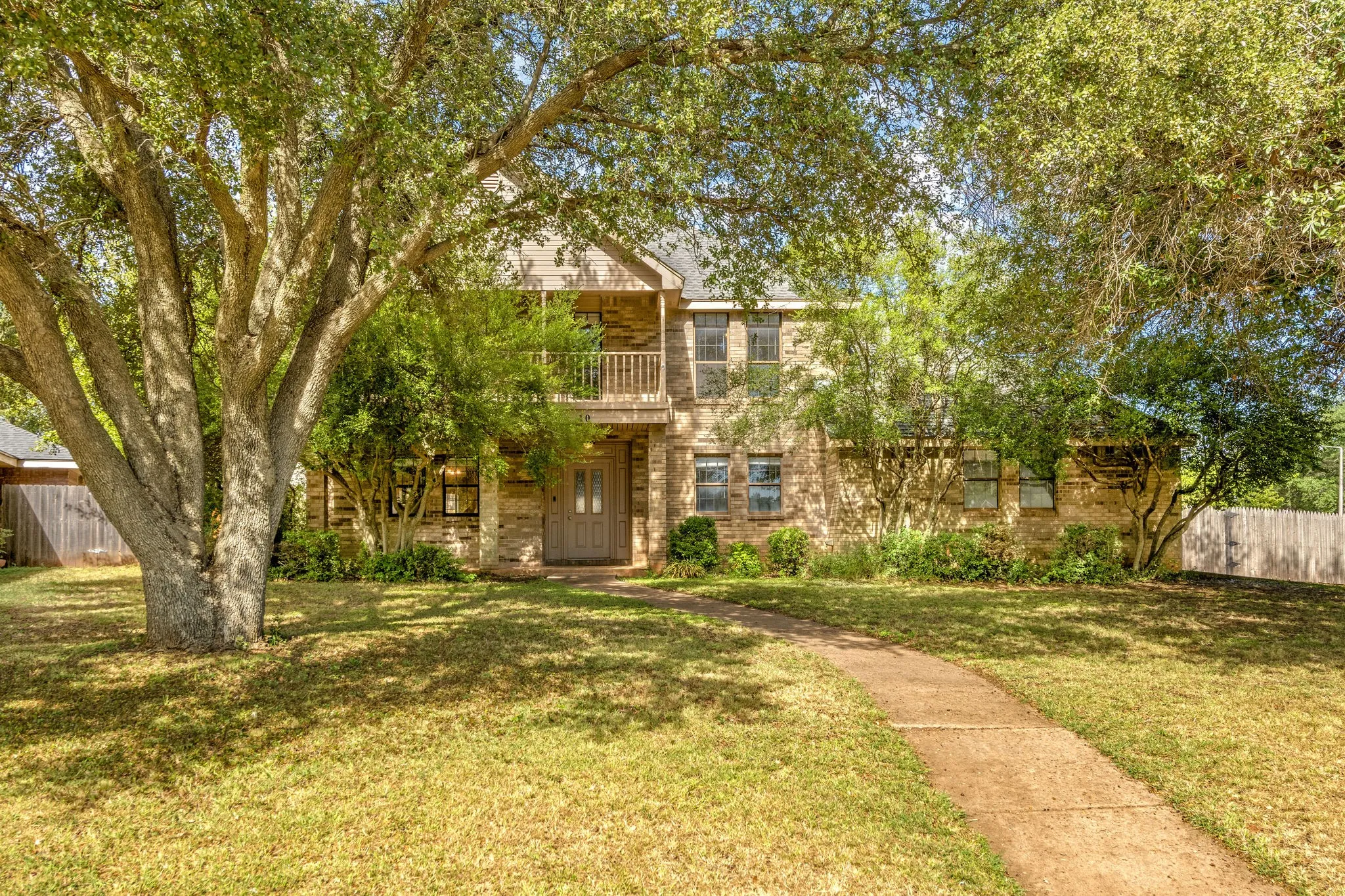 Beautiful large oak trees frame the two story brick home