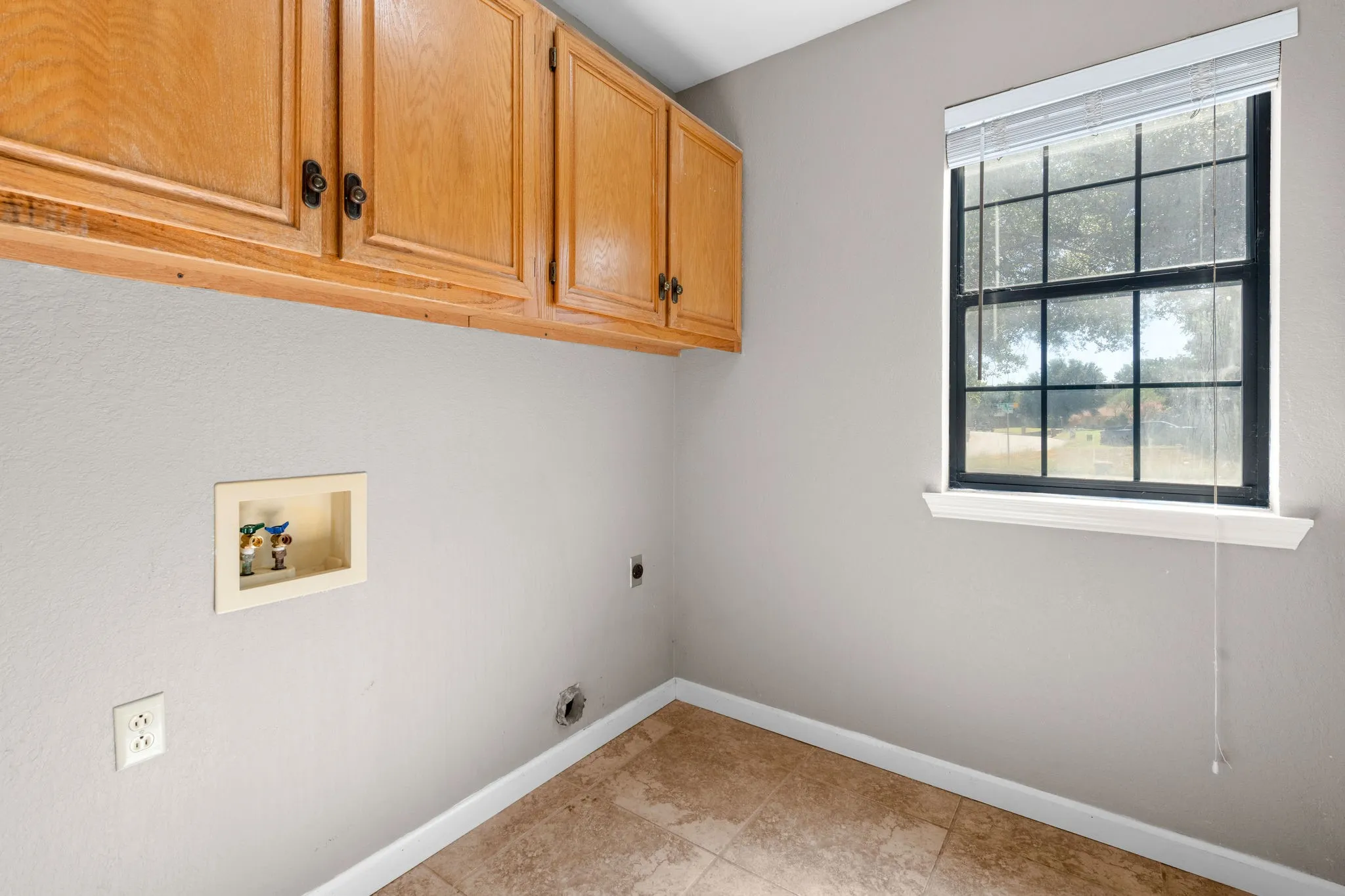Full Laundry room with built in storage and window to front tree shaded yard.