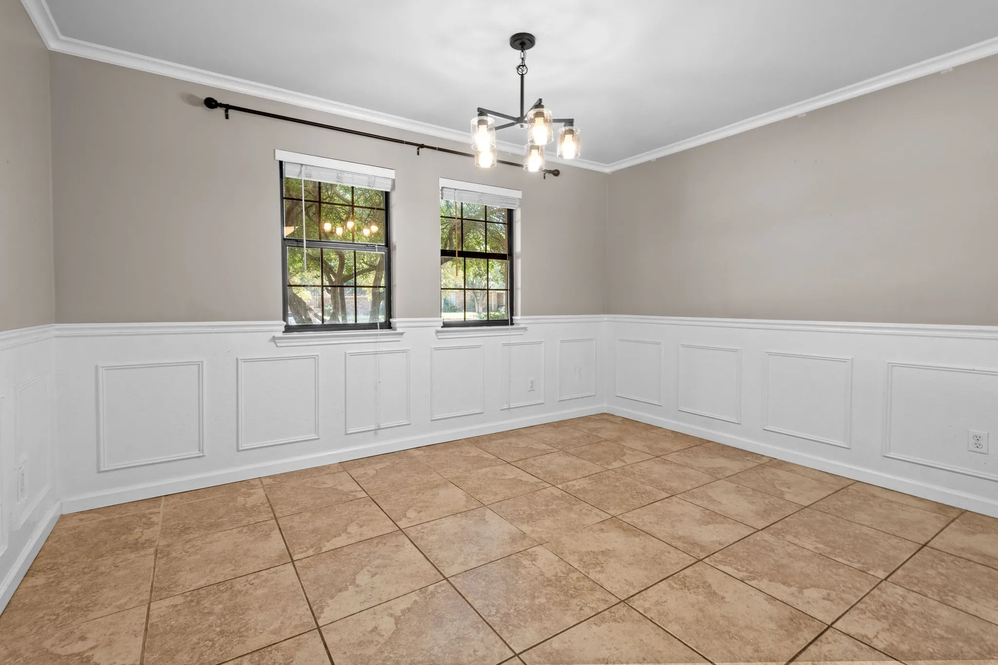 Dining area offers natural light and decorative wainscoting panels and tile floors.