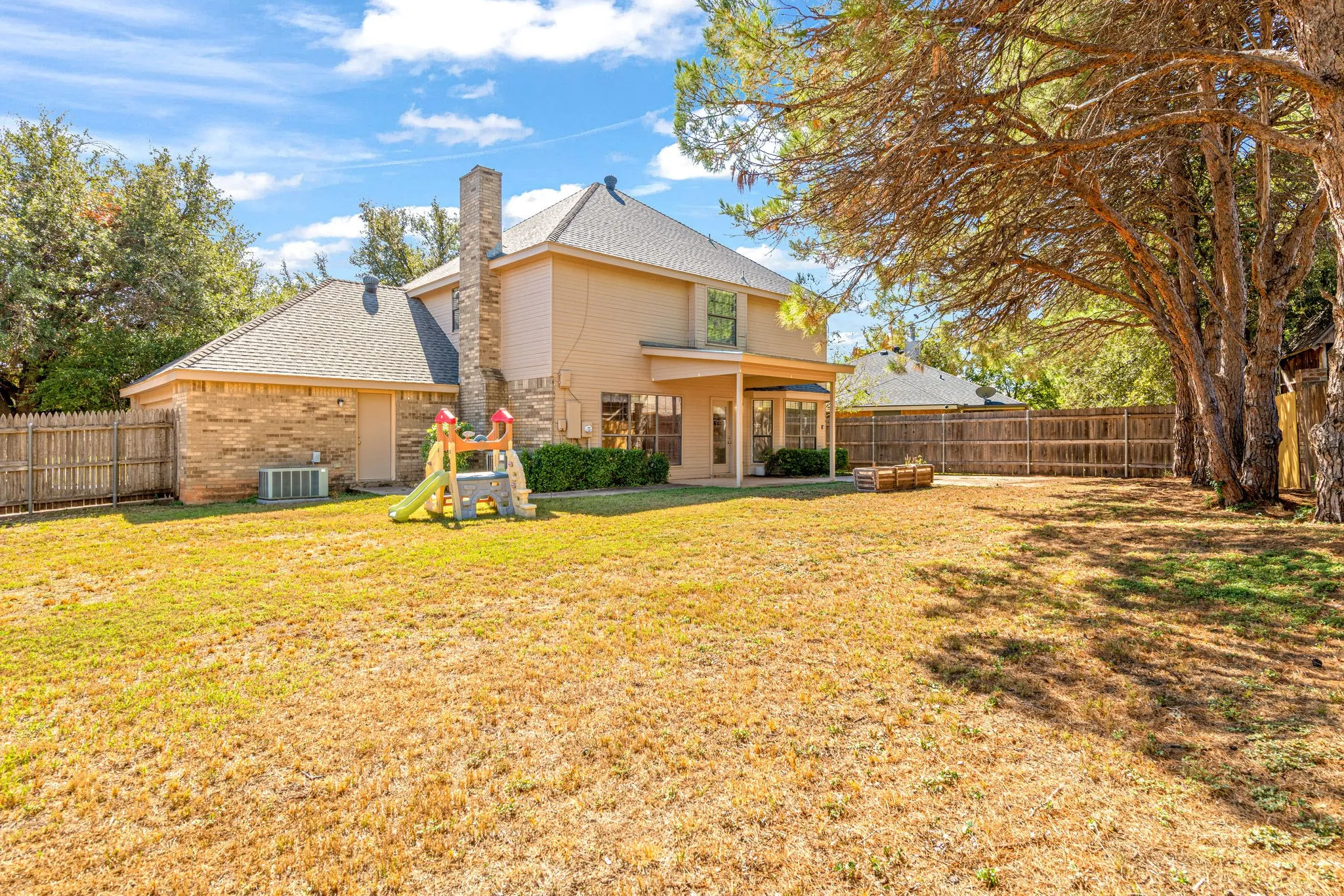 Back of home with large back yard, brick chimney.