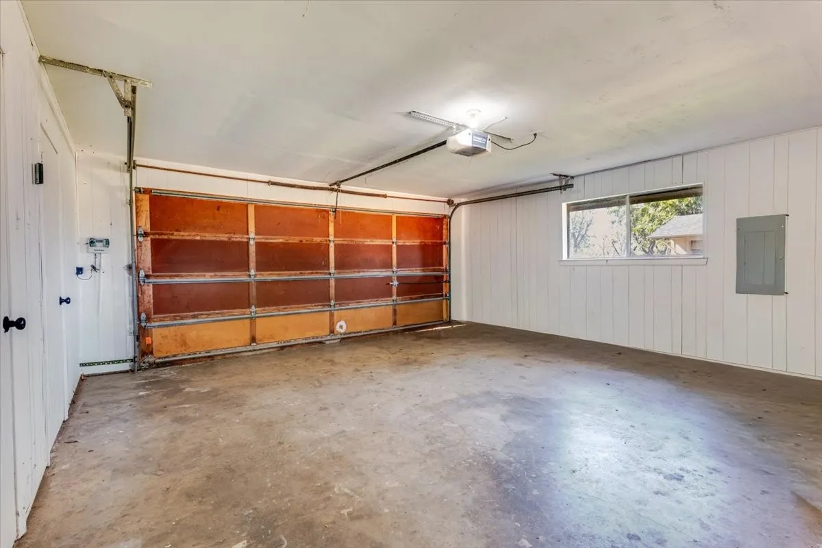 Spacious garage with a concrete floor, horizontal window, and panel-style walls