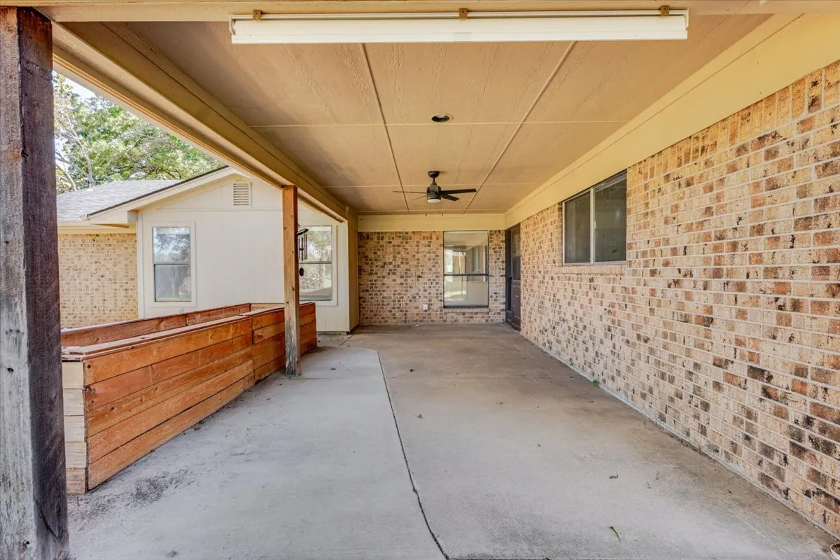 Covered concrete patio featuring a ceiling fan, recessed lighting, and brick exterior walls