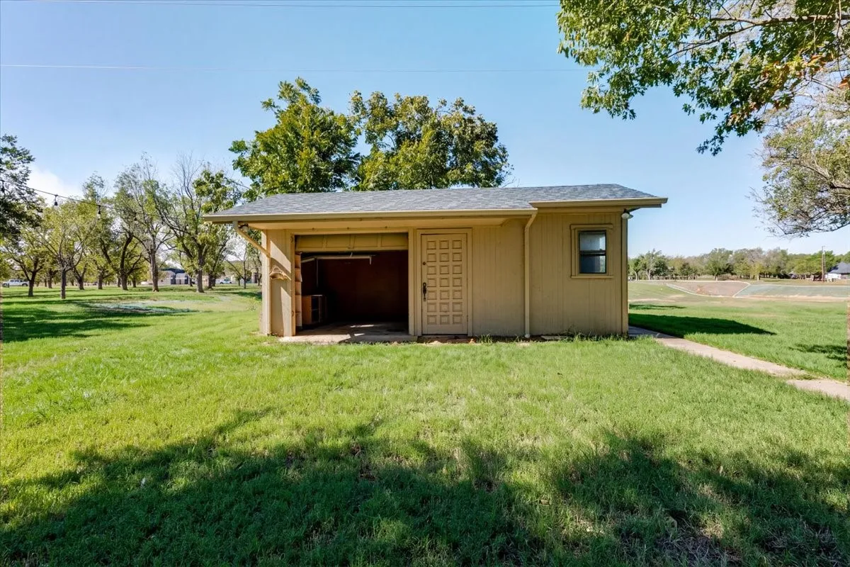 Detached utility building with a single window, a panel door, and an open bay area