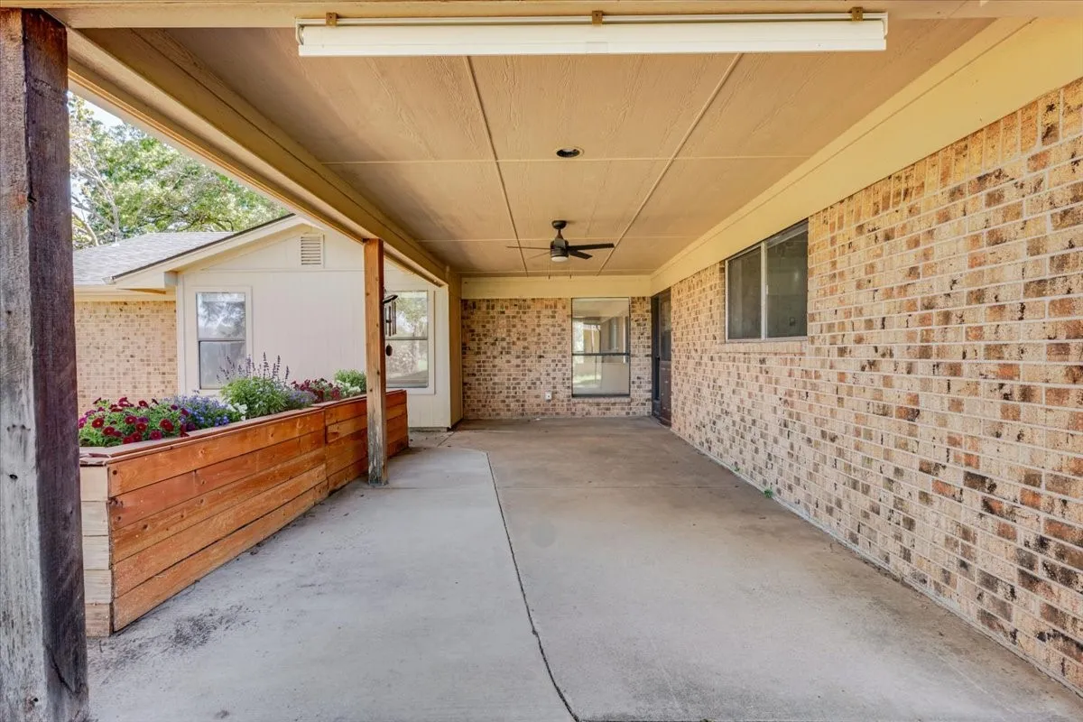 Covered patio with brick siding, concrete flooring, recessed lighting, and a ceiling fan -flowers virtually added