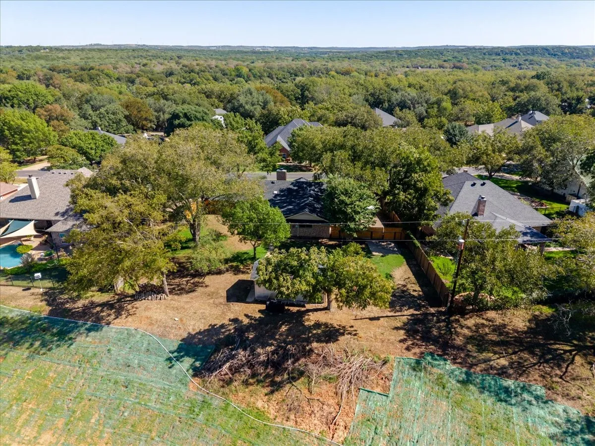 Expansive property with mature trees, a fenced perimeter, and a contemporary-style home featuring a dark roof