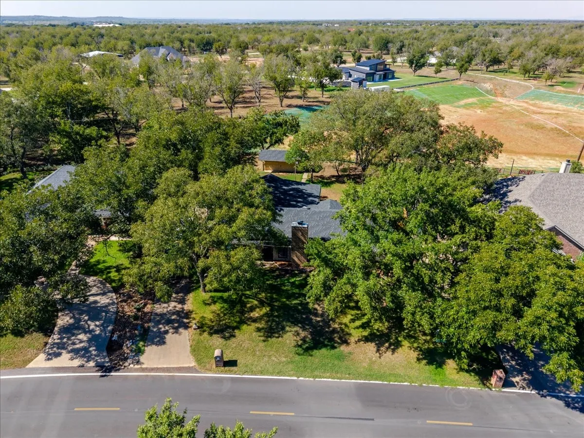 Property features a classic pitched roof, an attached garage, mature trees, and a concrete driveway