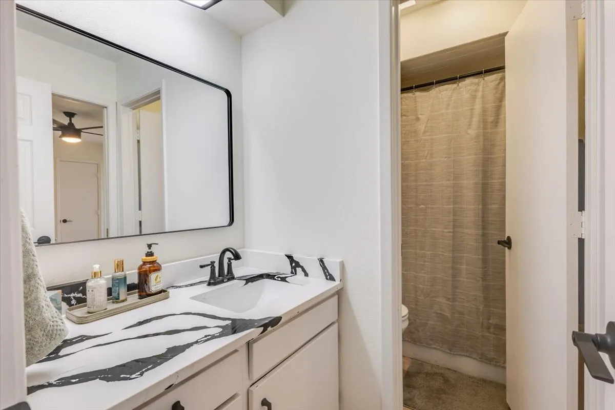 Vanity with a black and white patterned countertop, undermount sink, and matte black faucet