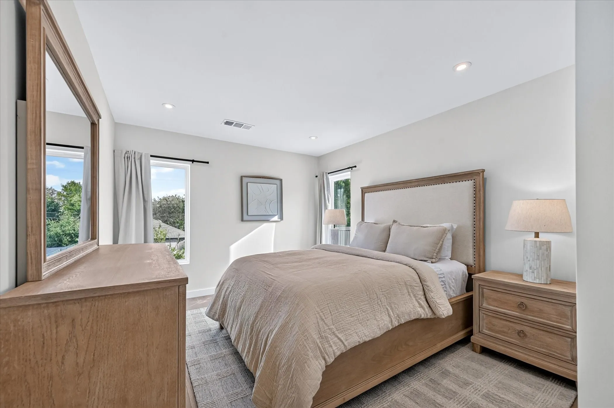 Recessed lighting, light-toned walls, wood-finish flooring, and multiple windows with outdoor scenery