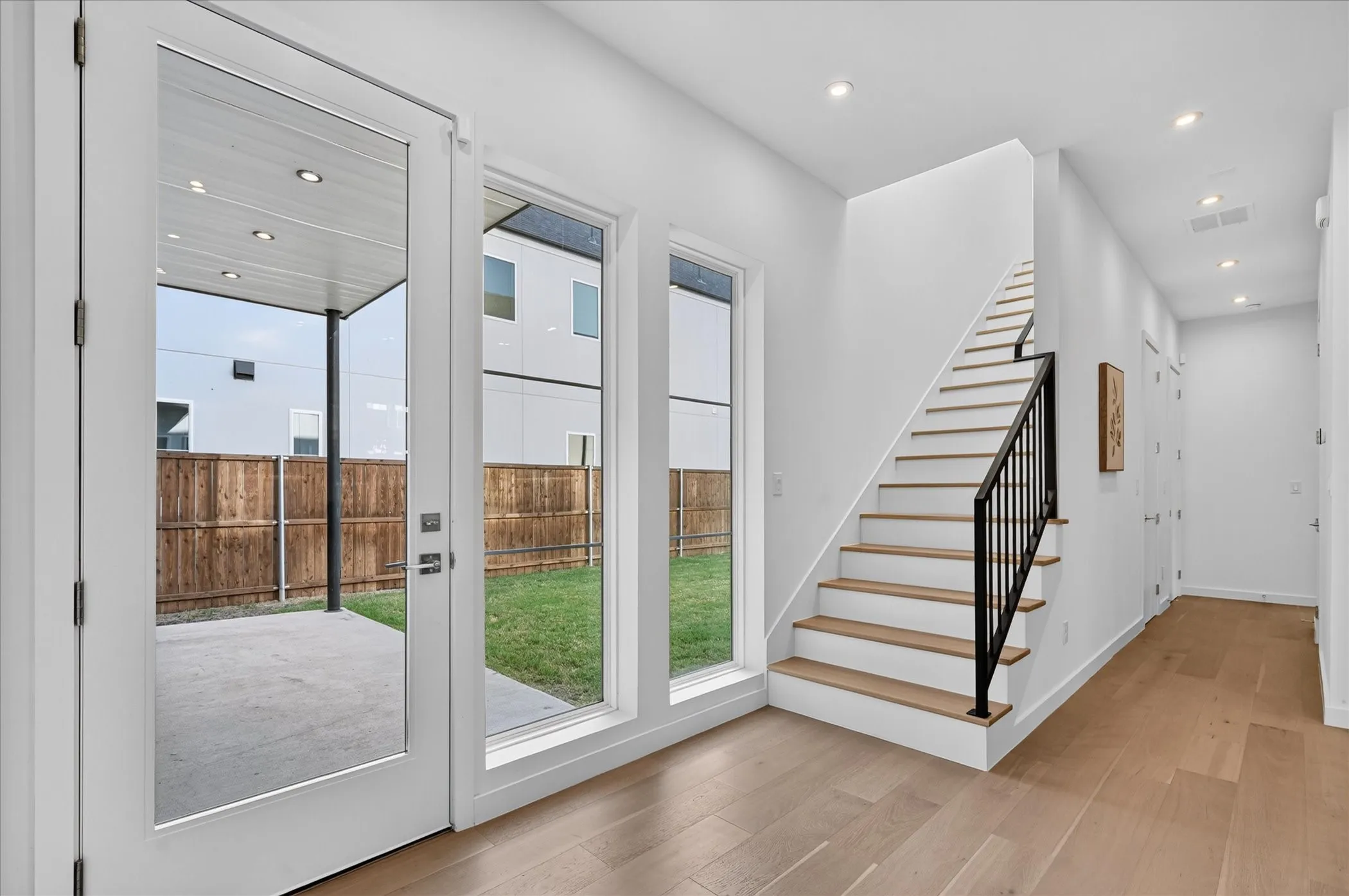 Wood-finish flooring, recessed lighting, and a contemporary staircase with a black metal railing