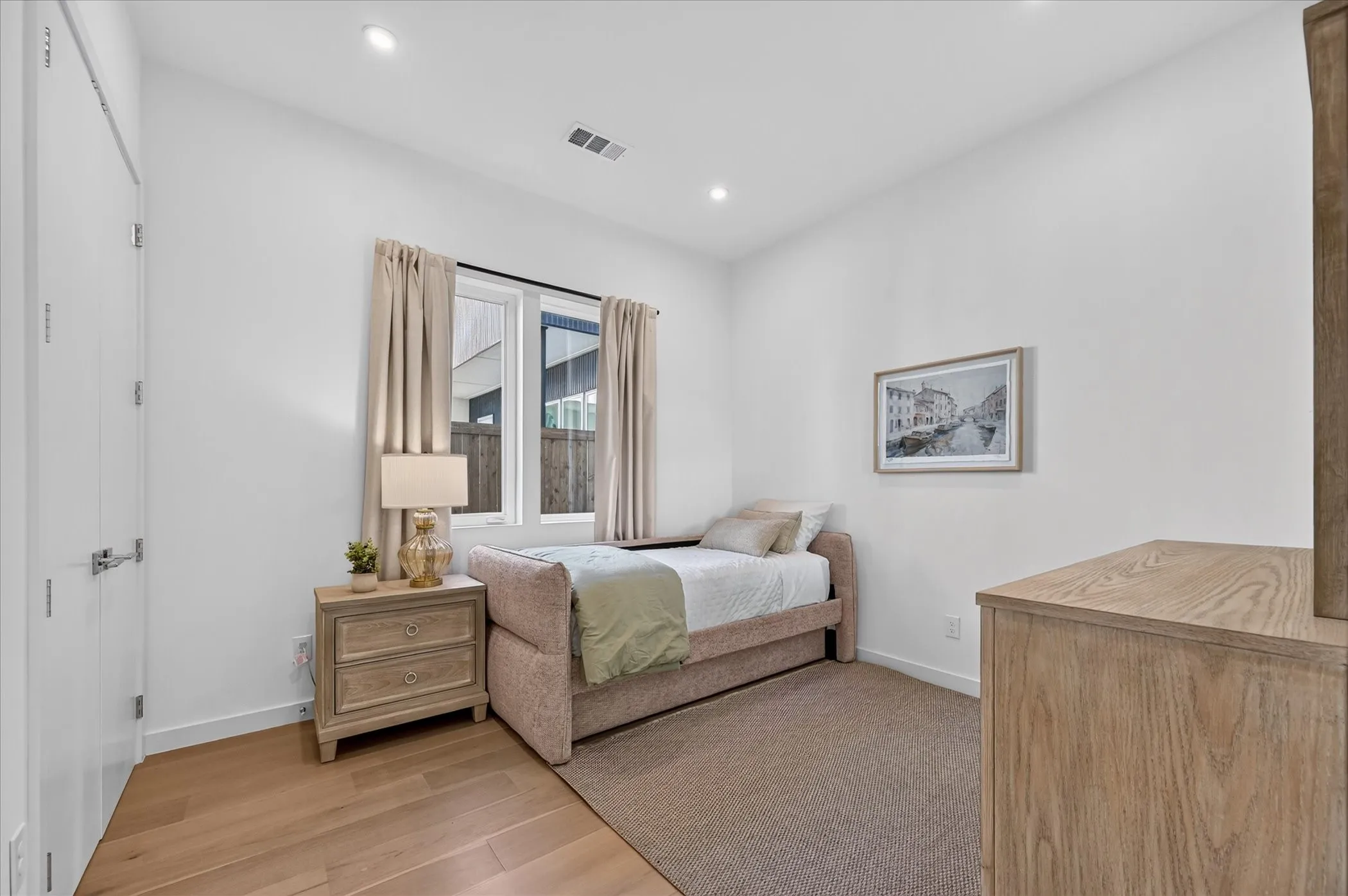 Recessed lighting, wood-finish flooring, and a large window providing natural light