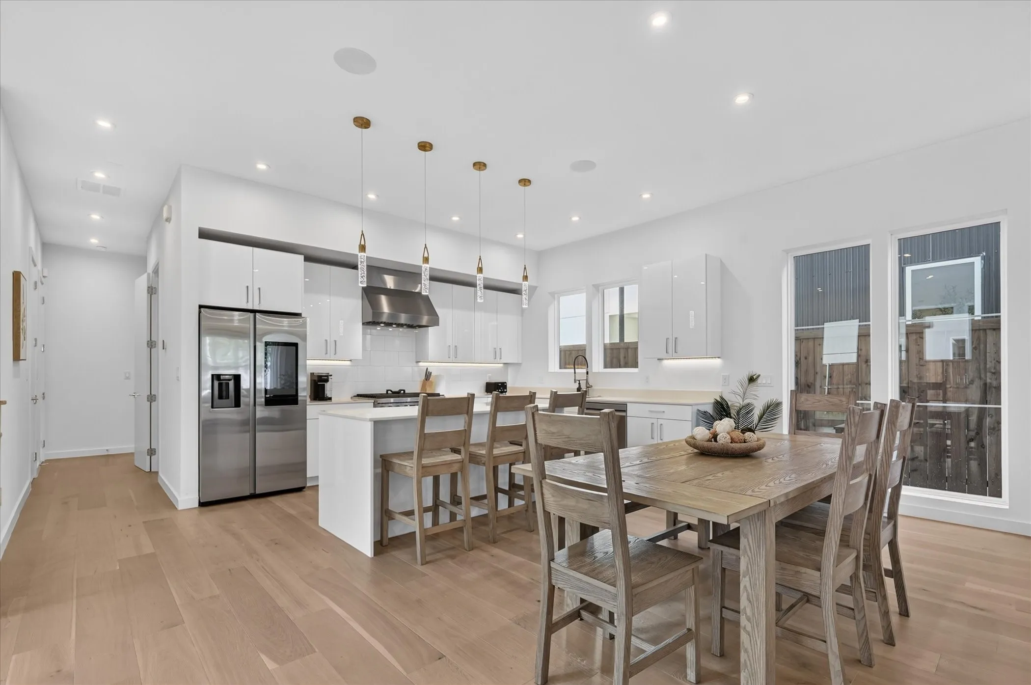 Open-concept kitchen with light wood-finish flooring, white cabinetry, stainless steel appliances, and recessed lighting