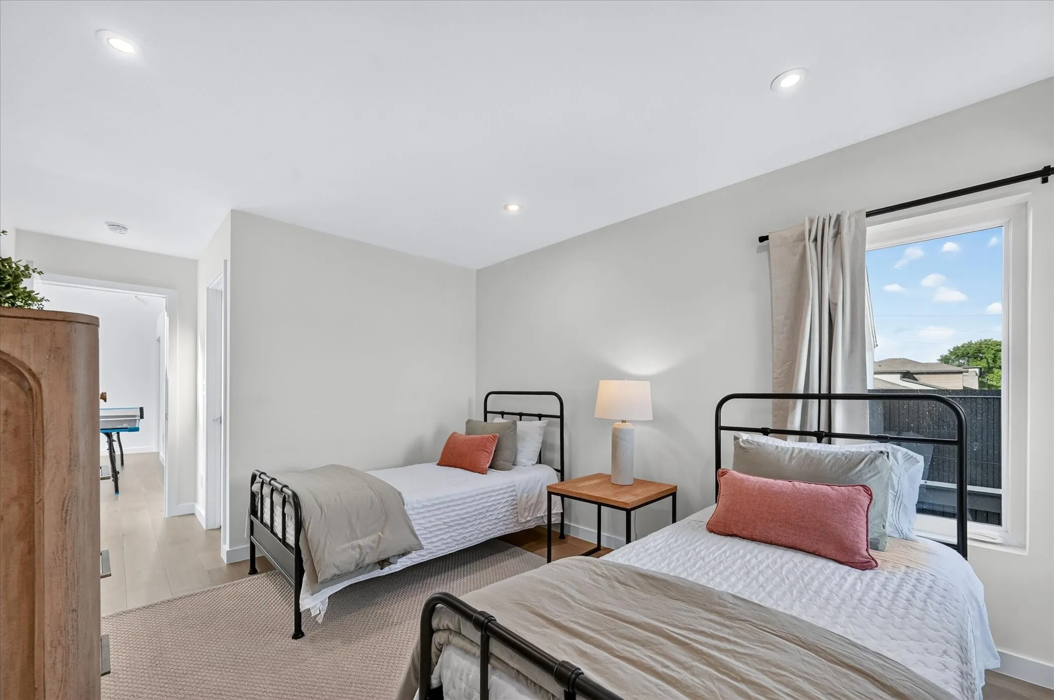 Recessed lighting, light wood-finish flooring, and a window with black trim