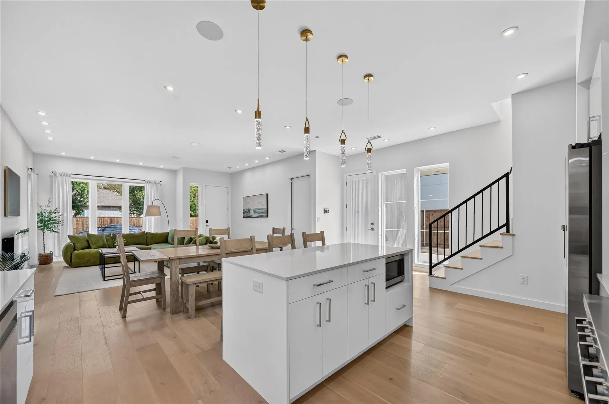 Open-concept living area with light wood-finish flooring, recessed lighting, and a kitchen island featuring a light-toned countertop