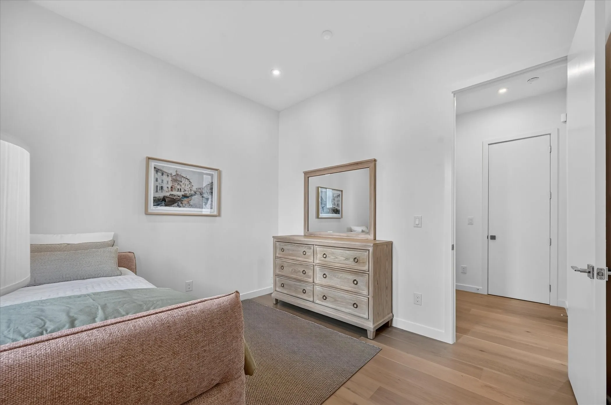 Hardwood flooring, recessed lighting, and a white interior door with brushed nickel hardware
