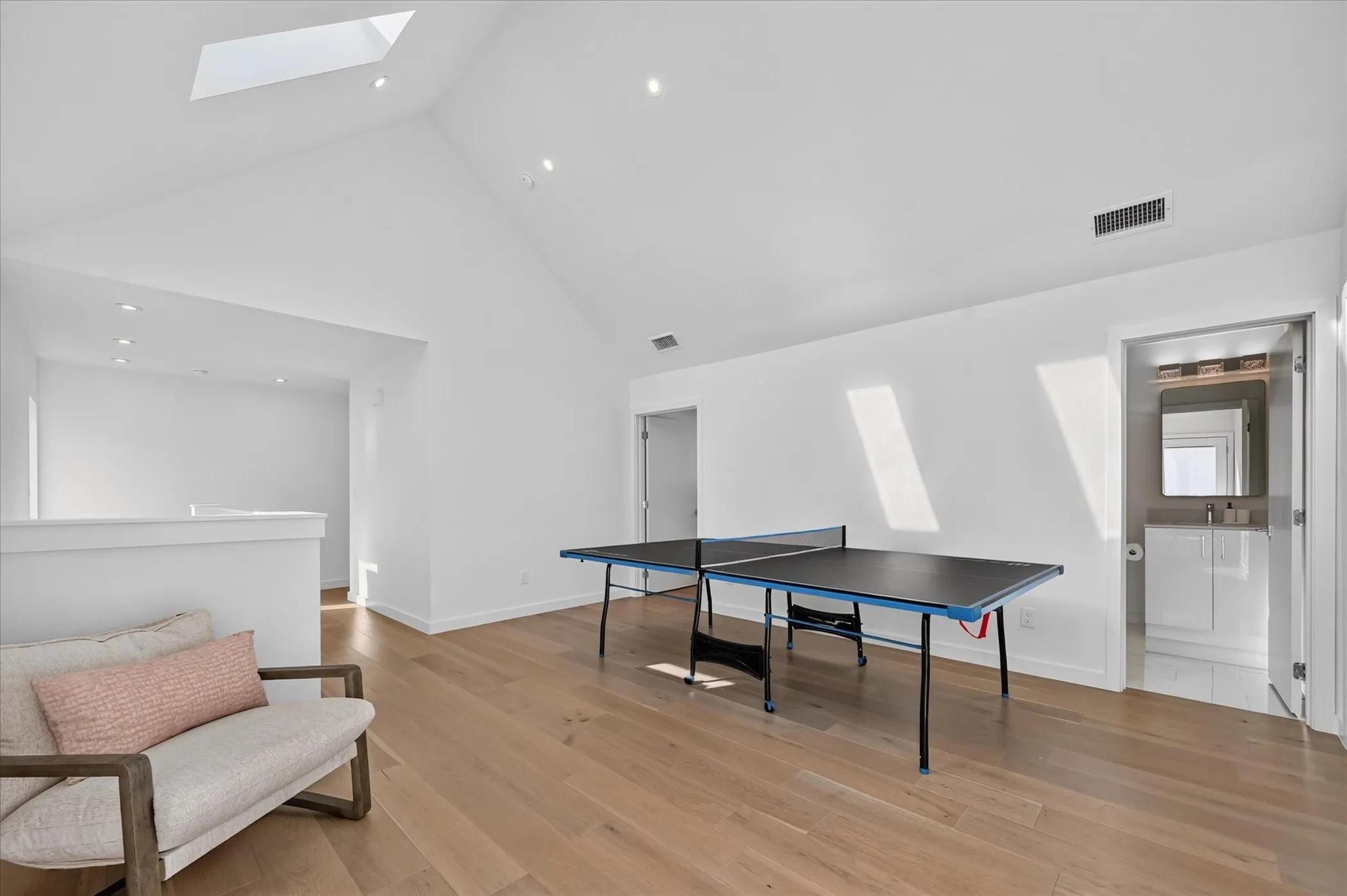 Vaulted ceiling with skylight, recessed lighting, and wood-finish flooring