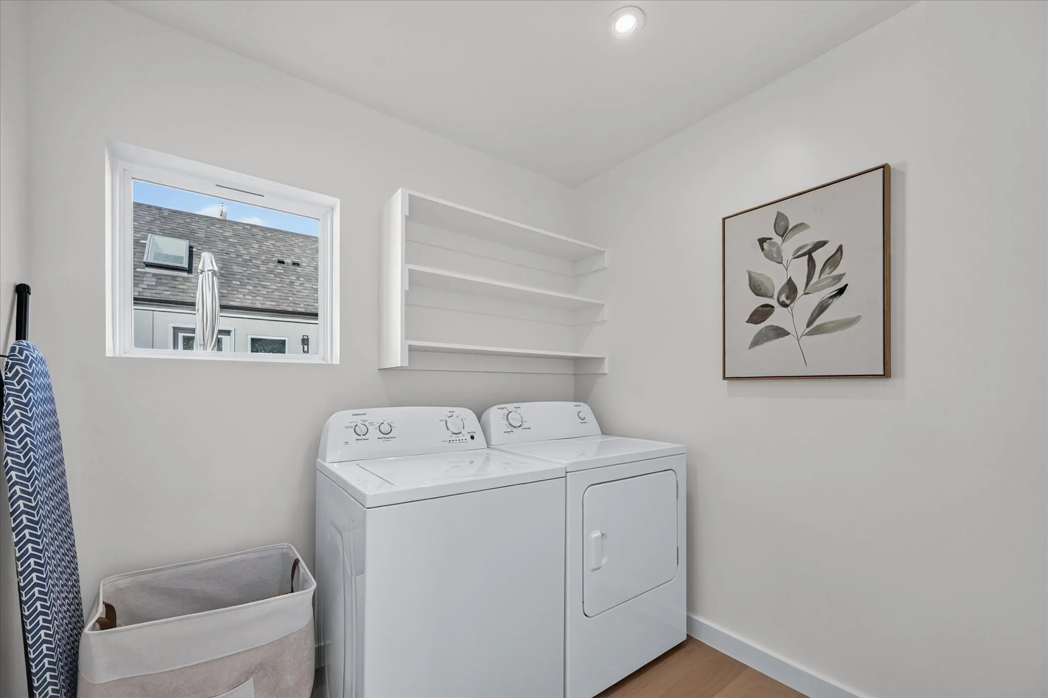 Laundry area featuring a window, built-in shelving, recessed lighting, and wood-finish flooring