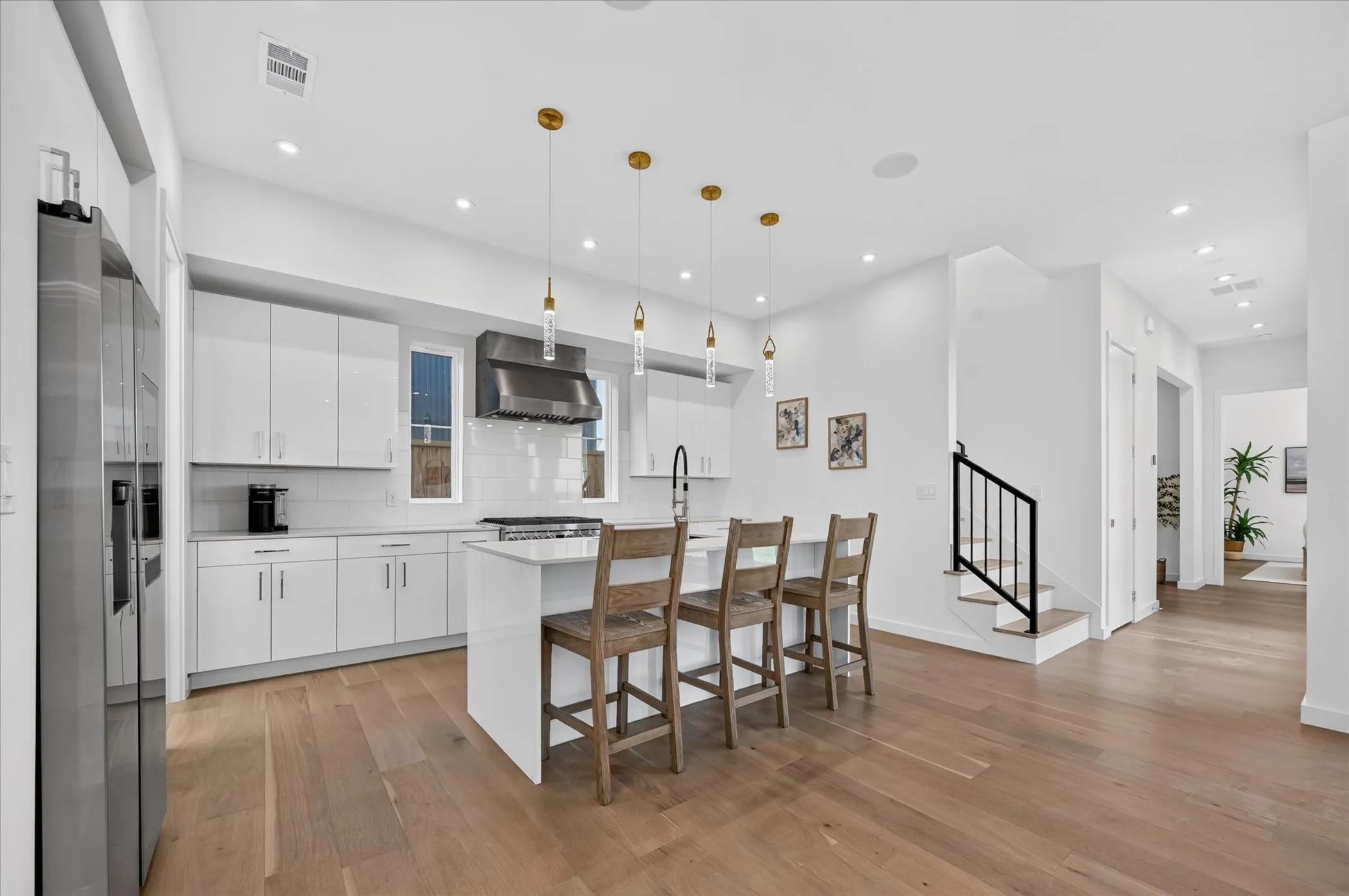 Gourmet kitchen with stainless steel appliances, white cabinetry, a center island, and pendant lighting