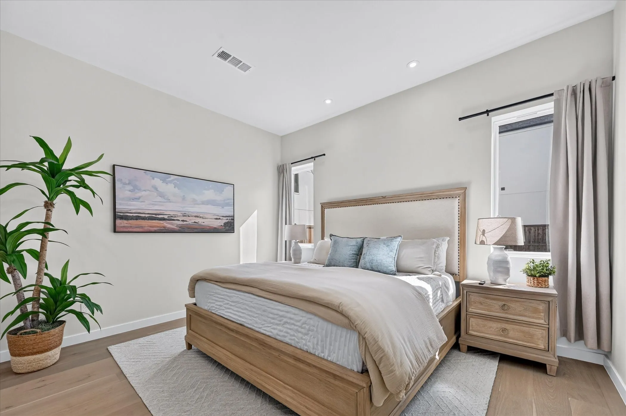 Recessed lighting, light wood-finish flooring, high ceilings, and windows with curtain rods