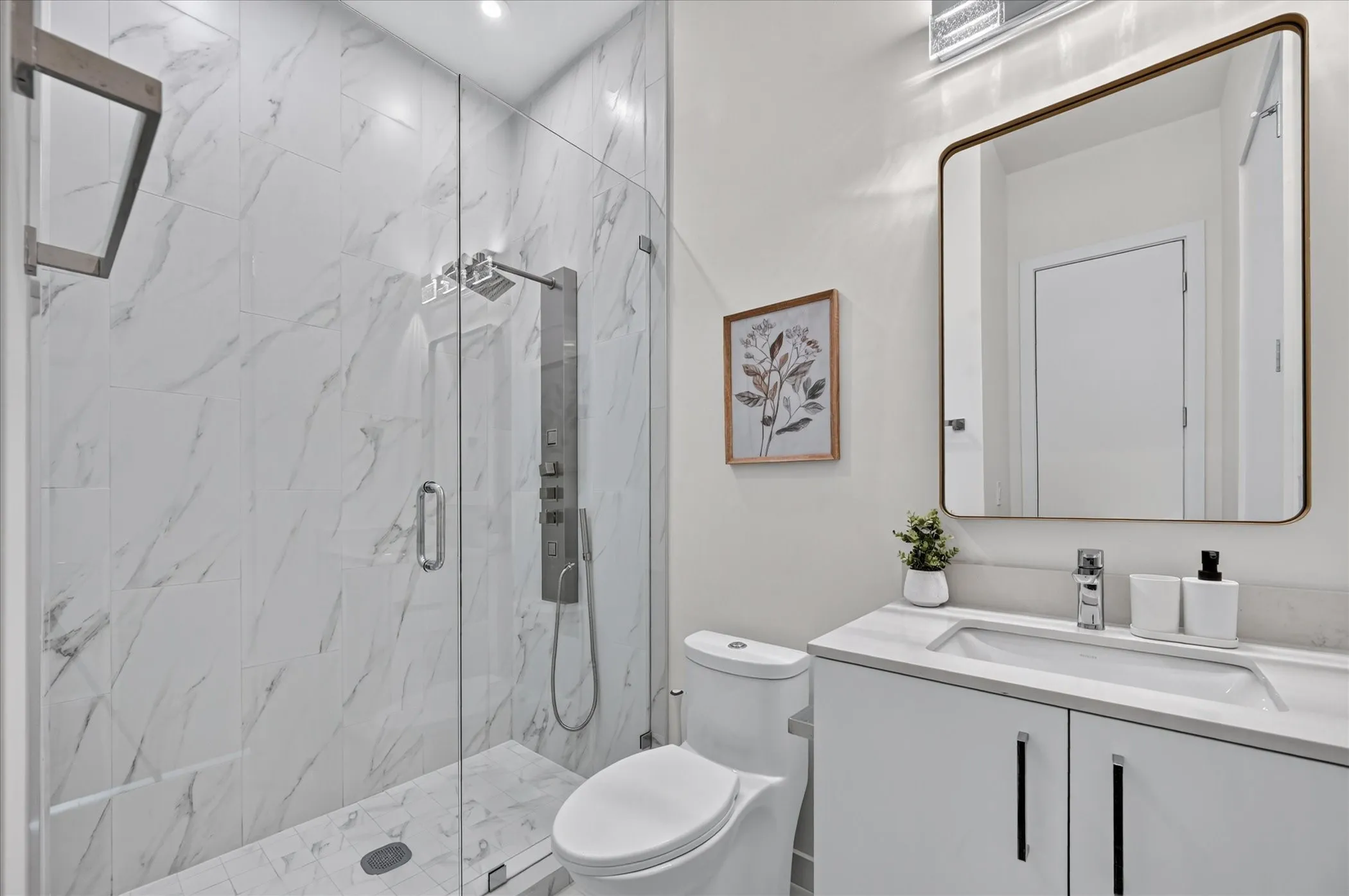 Glass-enclosed shower with a multi-function shower panel, white marble-look tile walls, and a matching tile shower pan