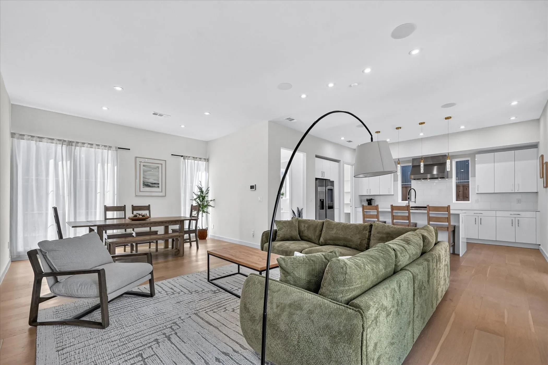 Open-concept living area with wood-finish flooring, recessed lighting, and large windows