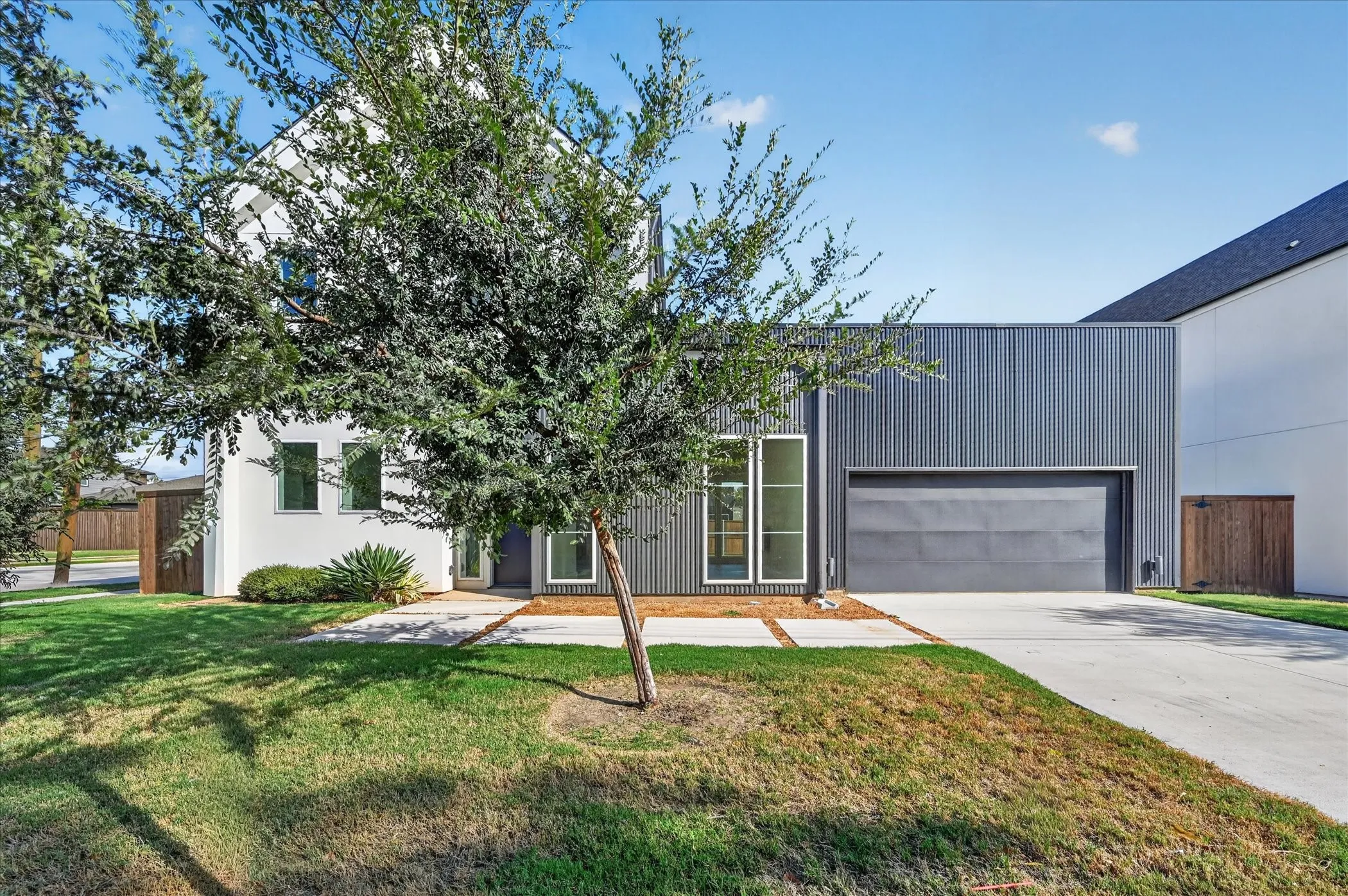 Modern residence featuring a clean-lined architectural design with mixed material exterior cladding, including corrugated metal paneling and stucco finishes