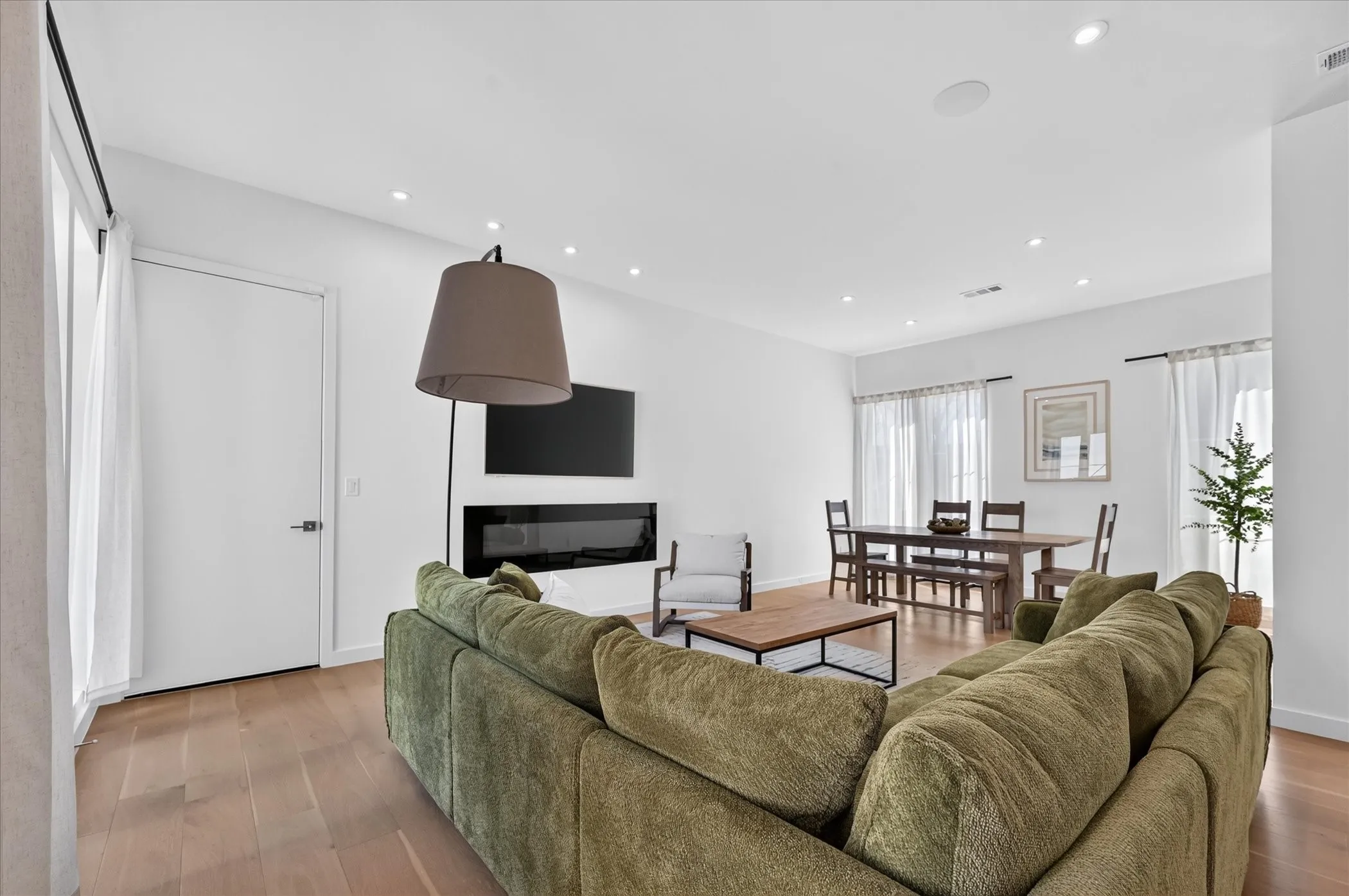 Open-concept living space featuring wood-finish flooring, recessed lighting, and an electric linear fireplace