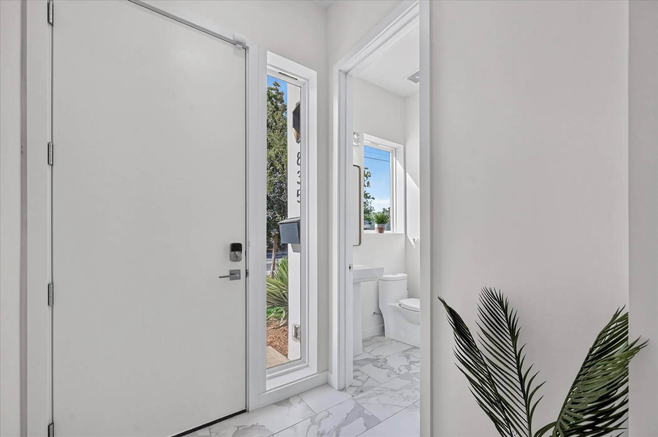 Entryway featuring a white door with smart lock hardware, a full-length sidelight, and marble-finish tile flooring