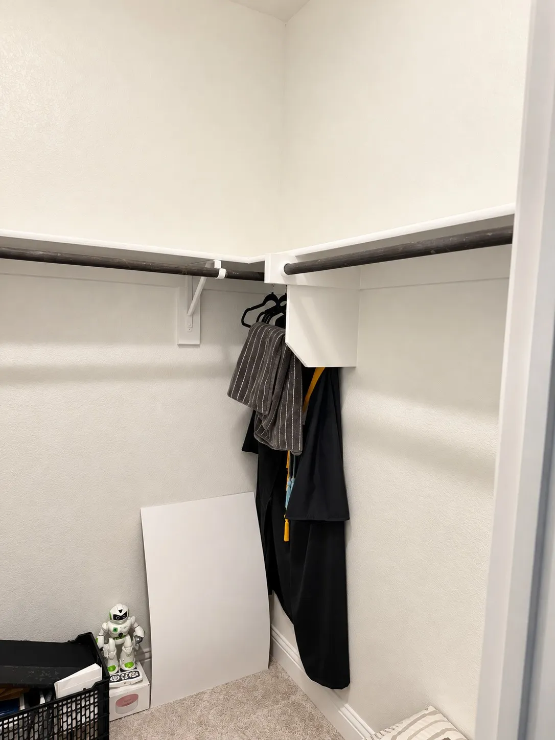 Wrap-around shelving with integrated garment rods, neutral wall finish, and a light-colored carpet