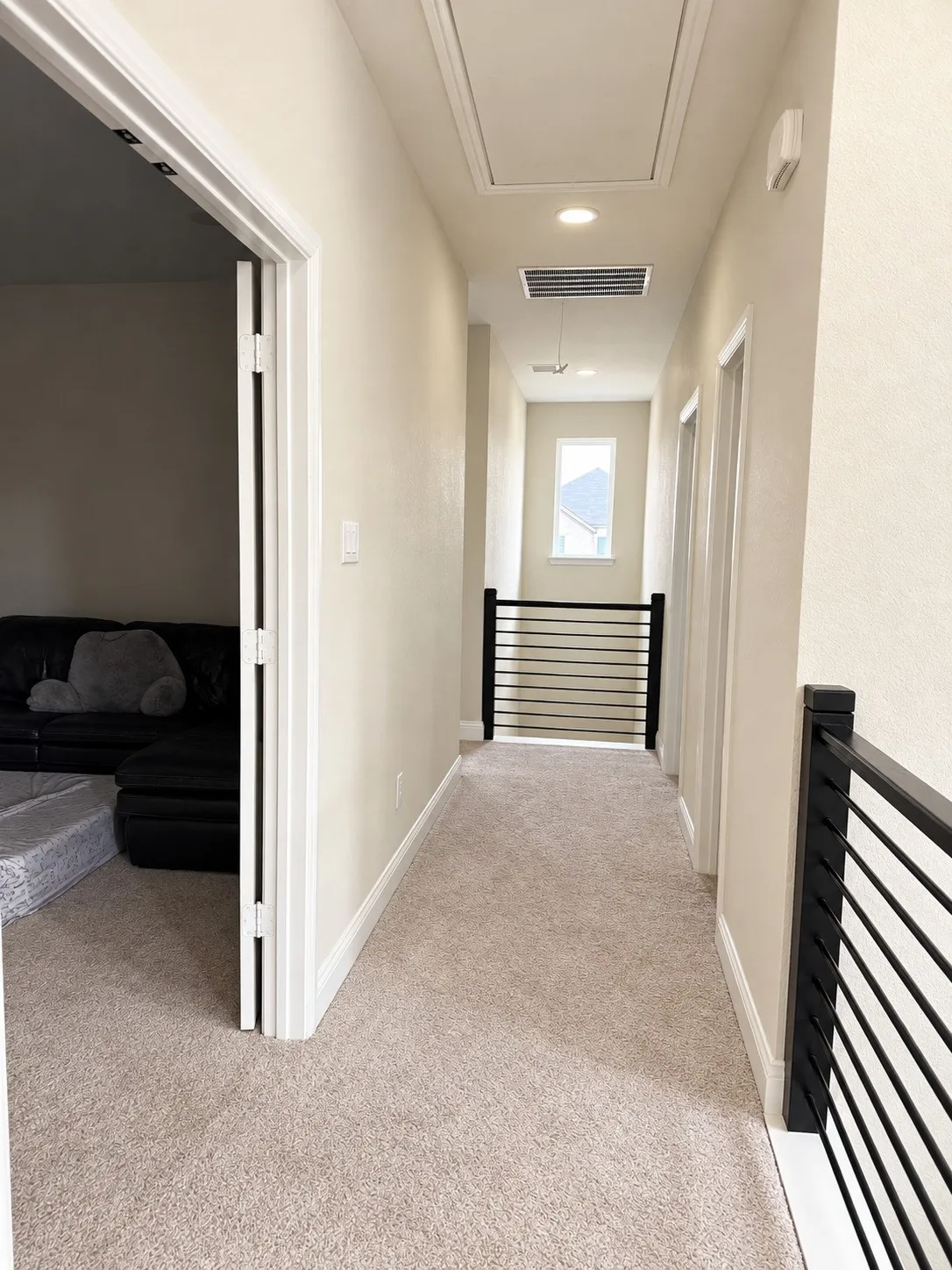 Light-toned wall paint, recessed lighting, carpeted hallway, and black metal railings