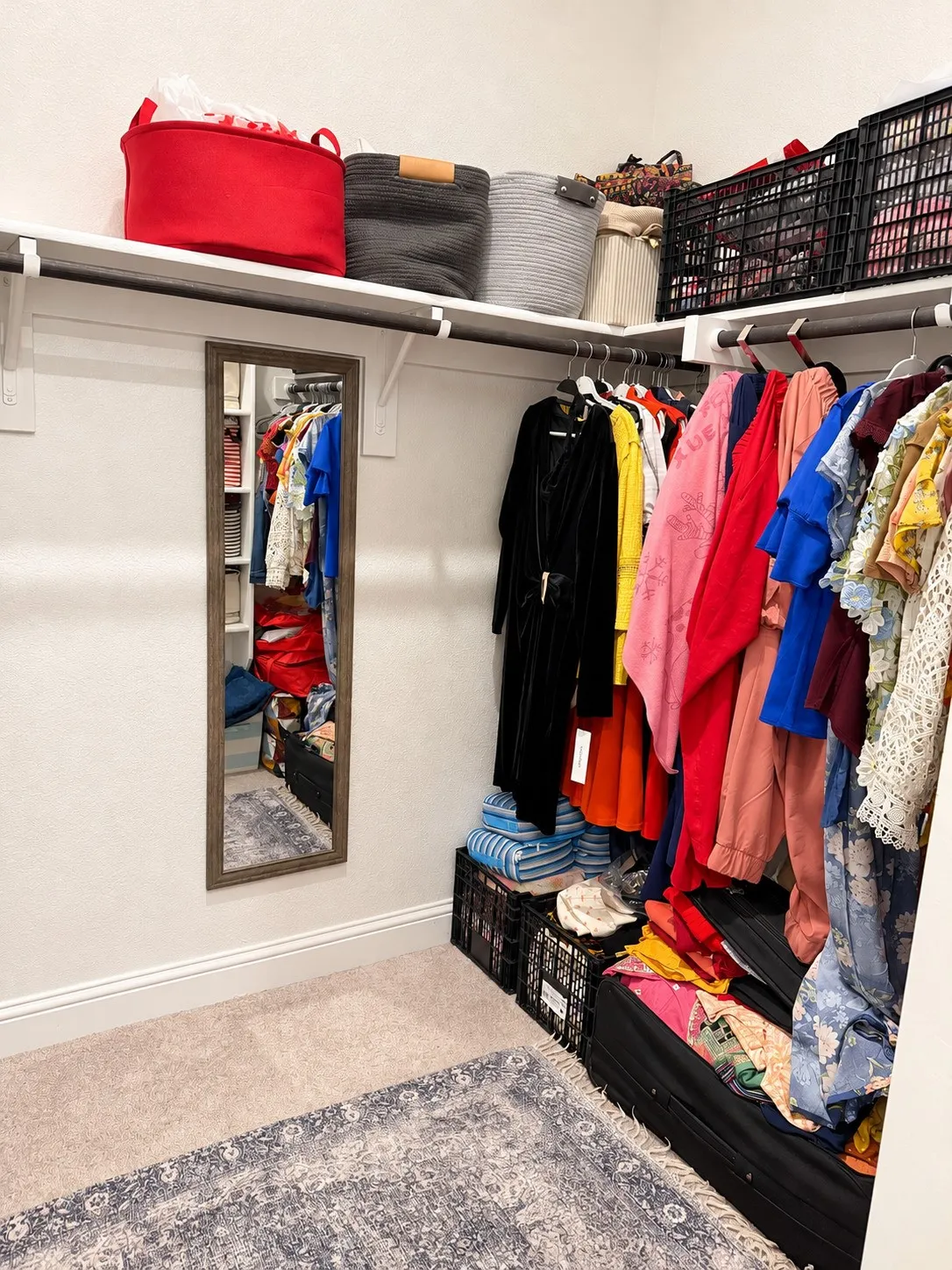 Built-in closet shelving and hanging rods with a full-length mirror and carpeted flooring