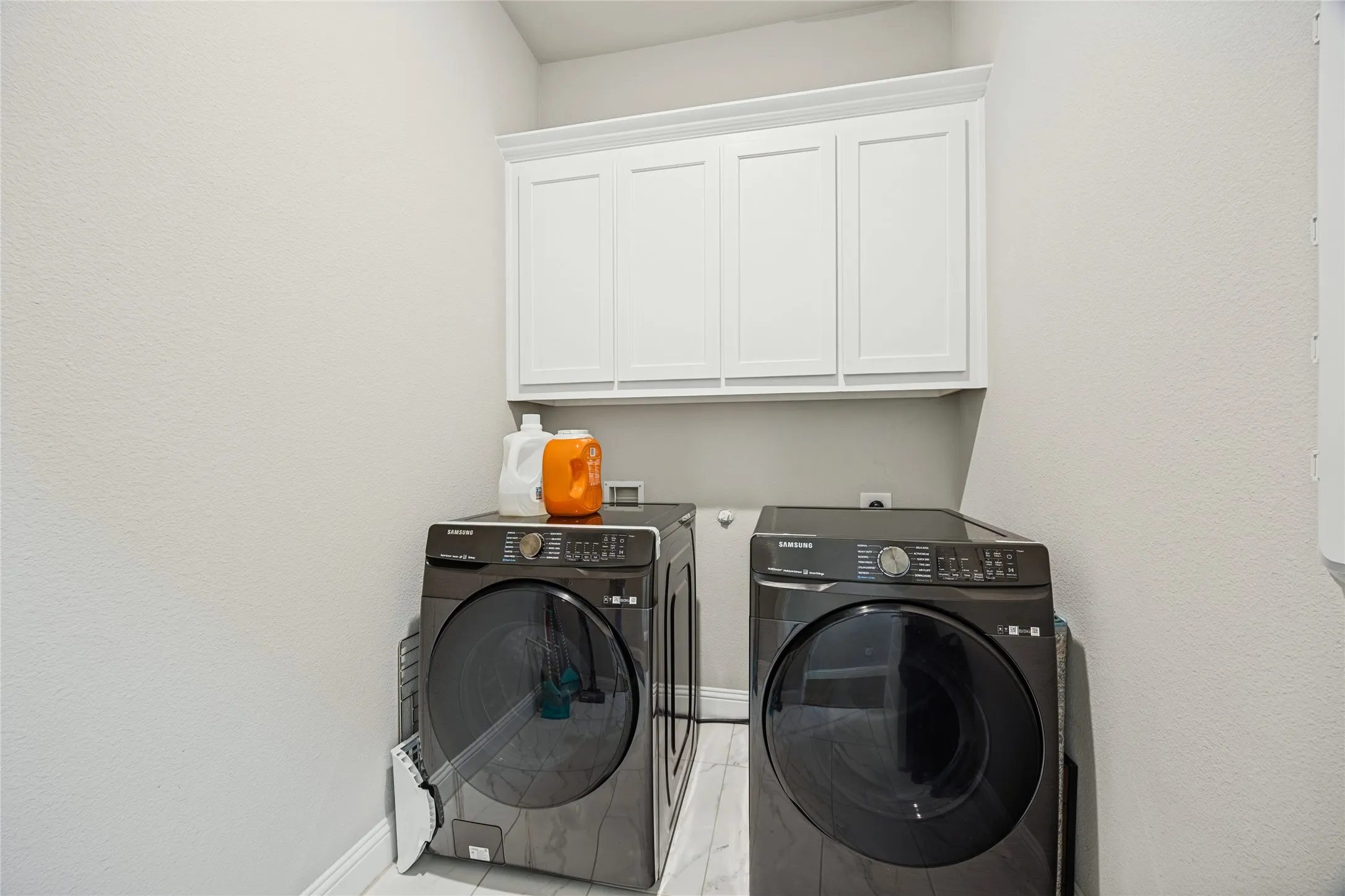 White shaker-style cabinetry with crown molding, light-toned walls, and a durable tile flooring
