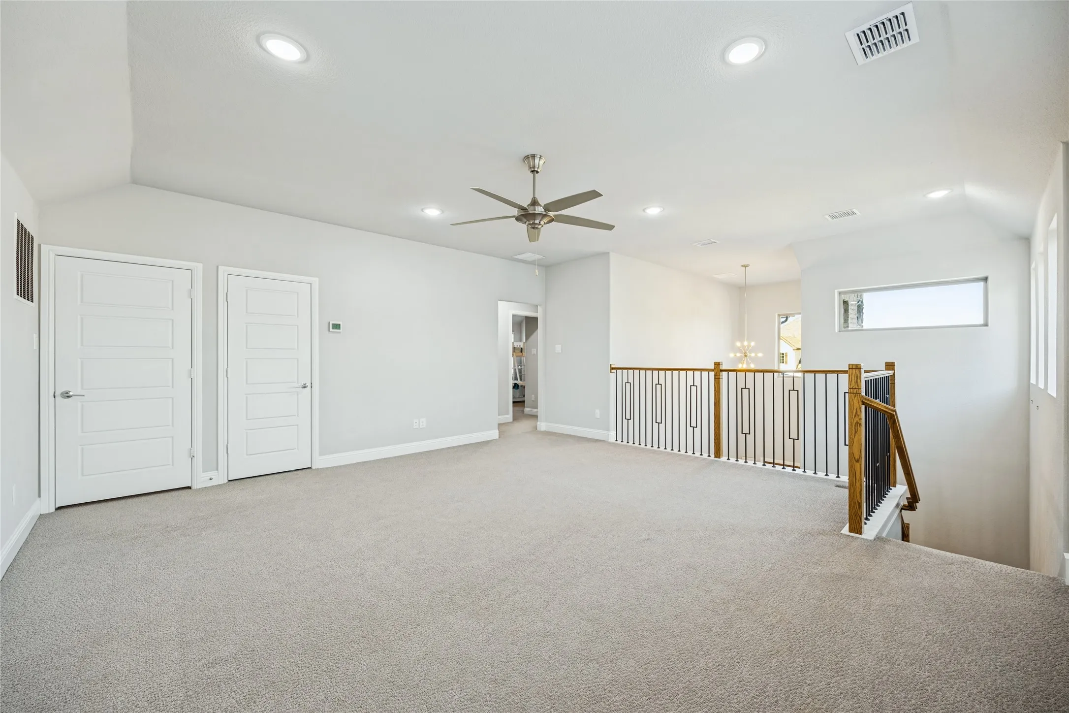 Spacious carpeted room featuring vaulted ceilings, recessed lighting, and a ceiling fan
