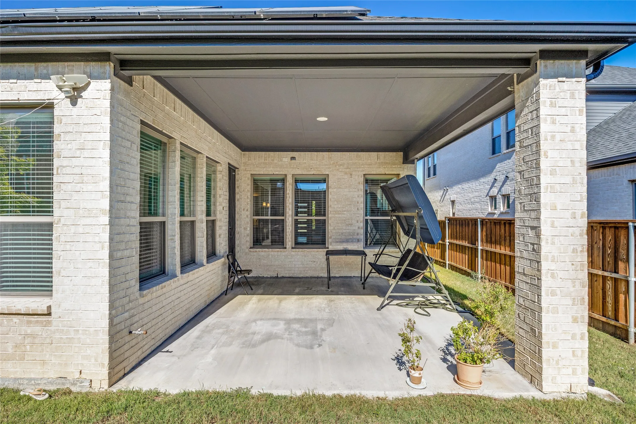Covered patio with a concrete surface, white brick exterior, and recessed lighting