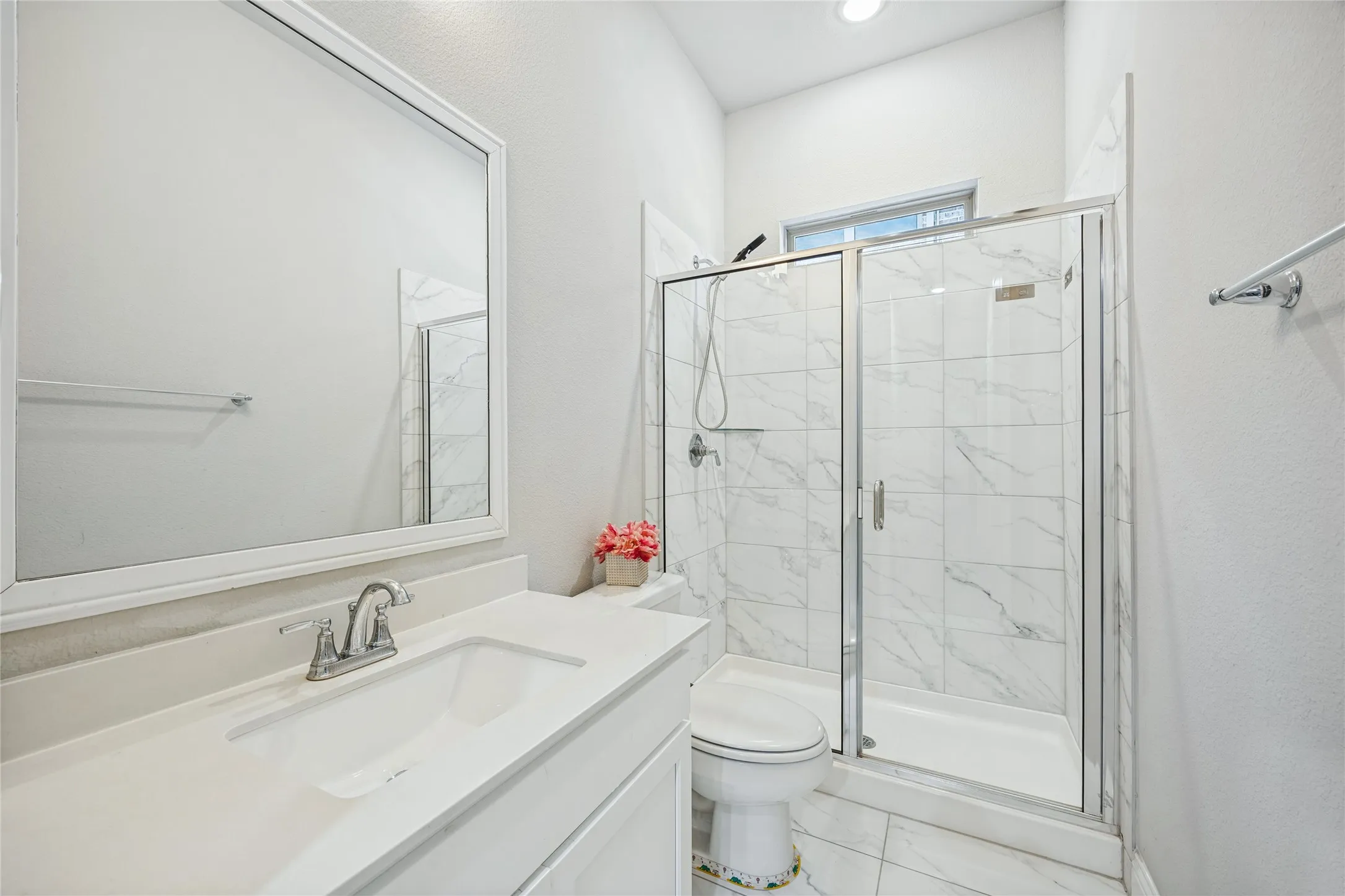 Vanity with a single basin, walk-in shower with clear glass enclosure, marble-look tile, and recessed lighting