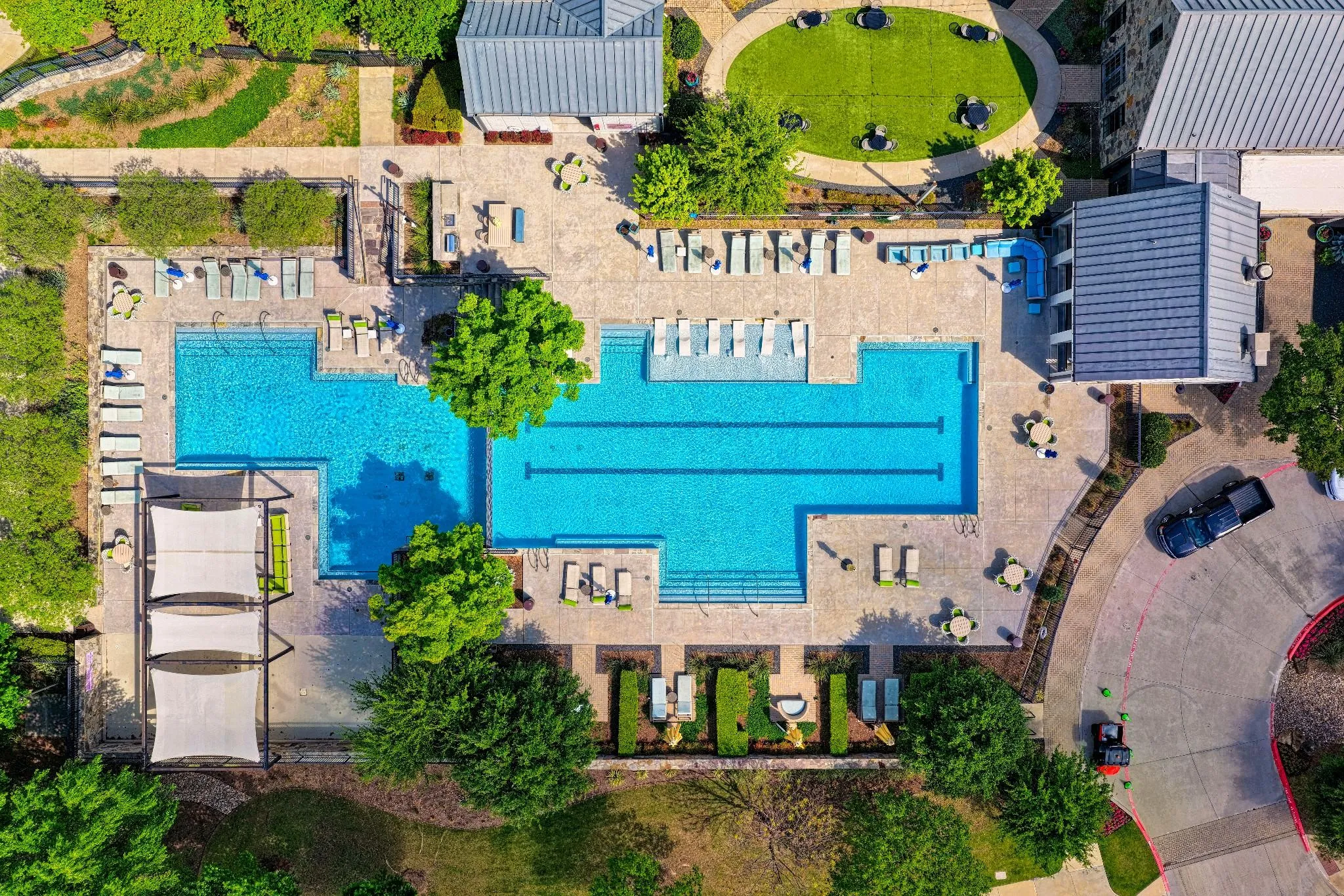 Expansive swimming pool area featuring a multi-lane lap pool, additional wading pool, and surrounding hardscaping