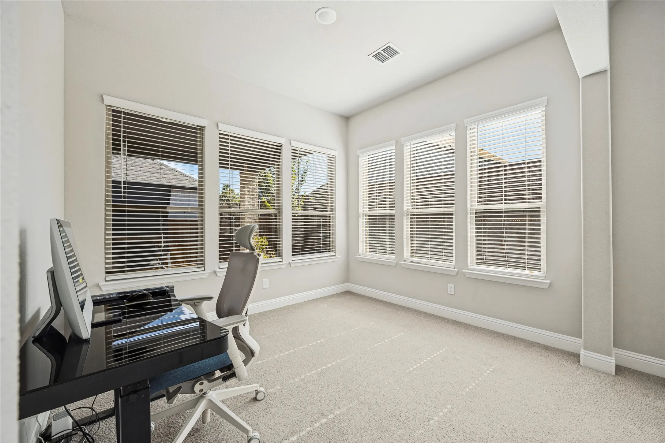 Neutral color palette with recessed lighting, multiple windows, and light-colored carpeting
