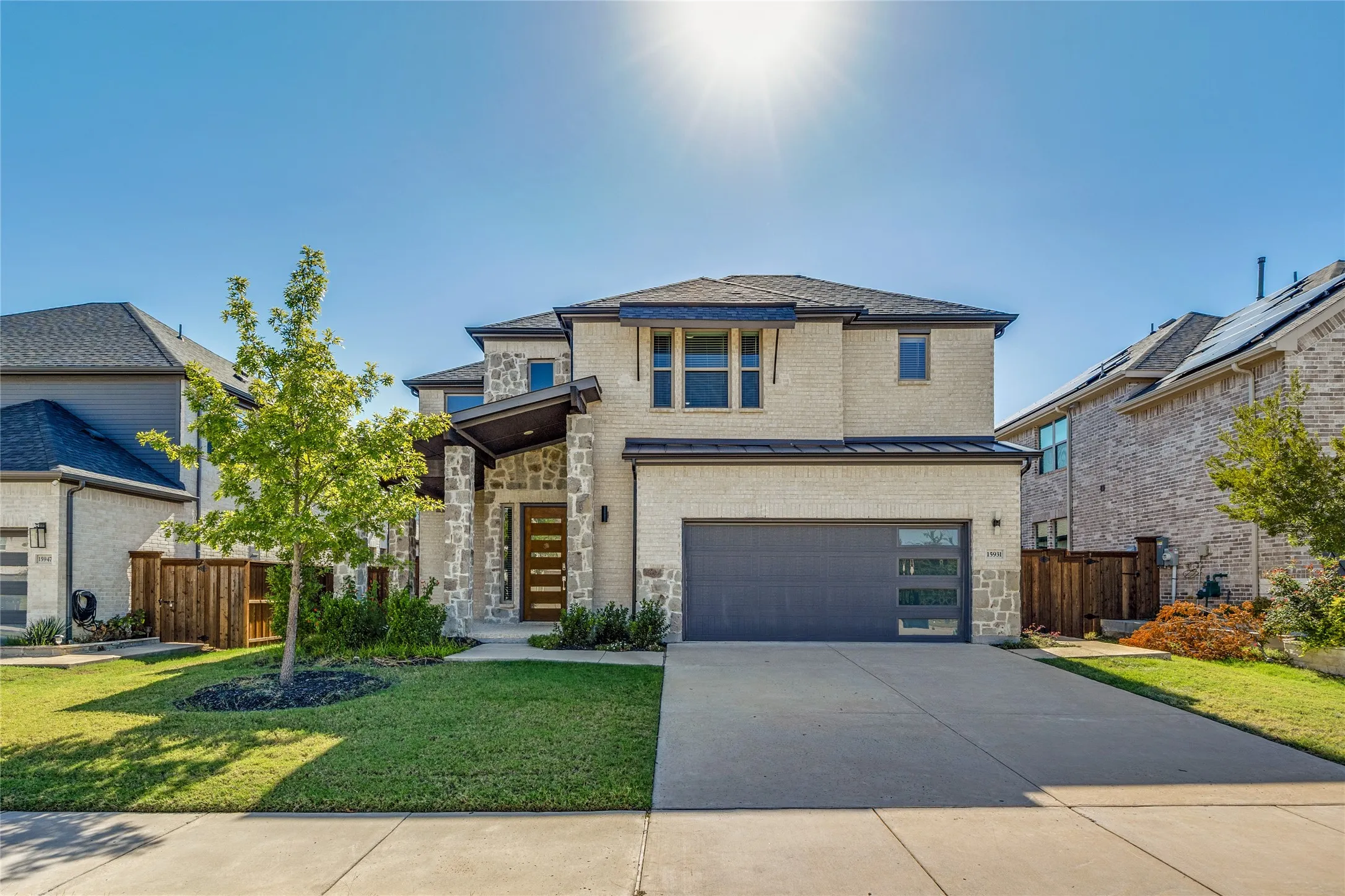 Stone and stucco exterior with a dark trim roof, featuring a wood-panel front door and an integrated garage