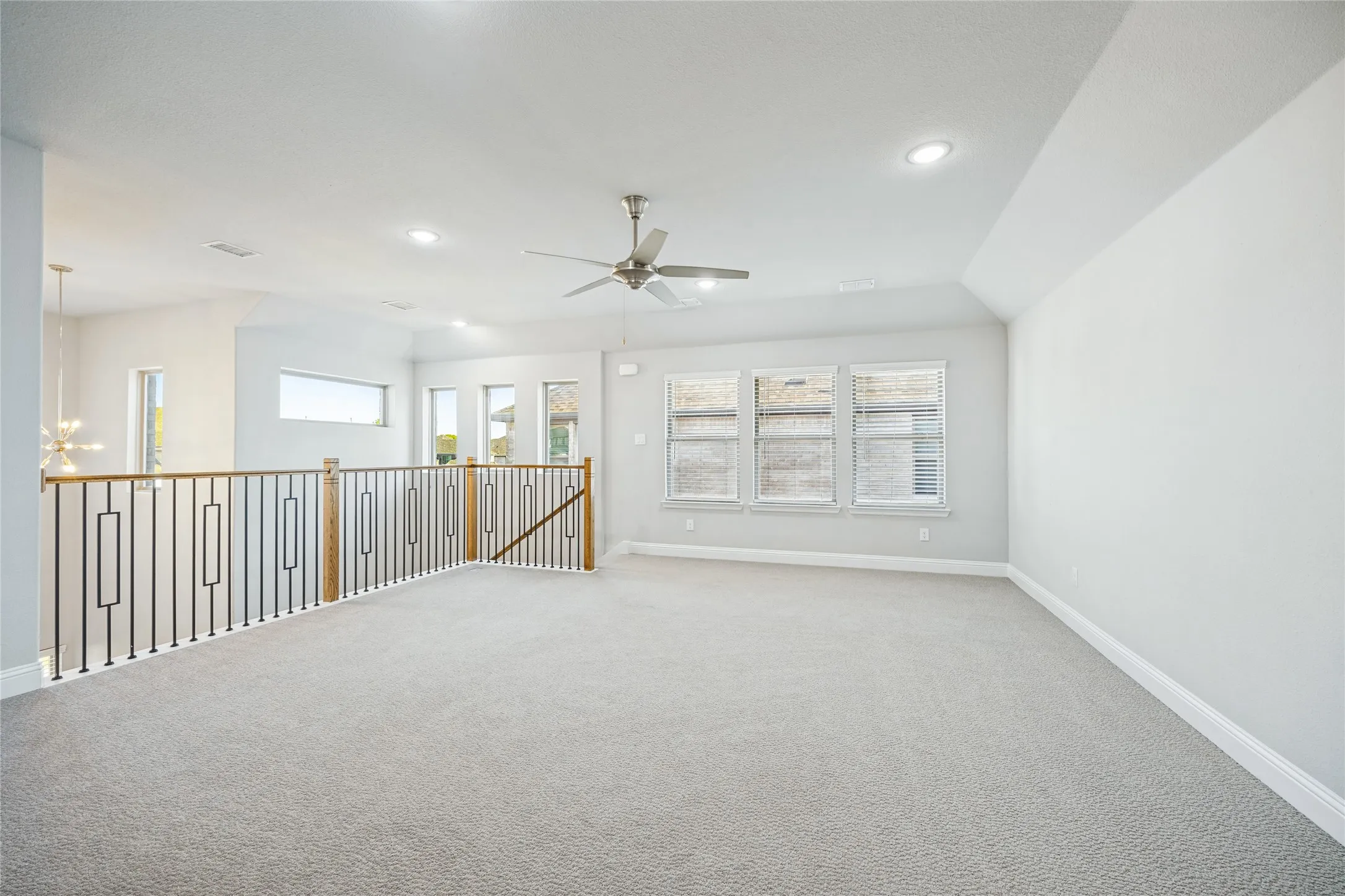 Open loft space with light-toned carpeting and multiple windows