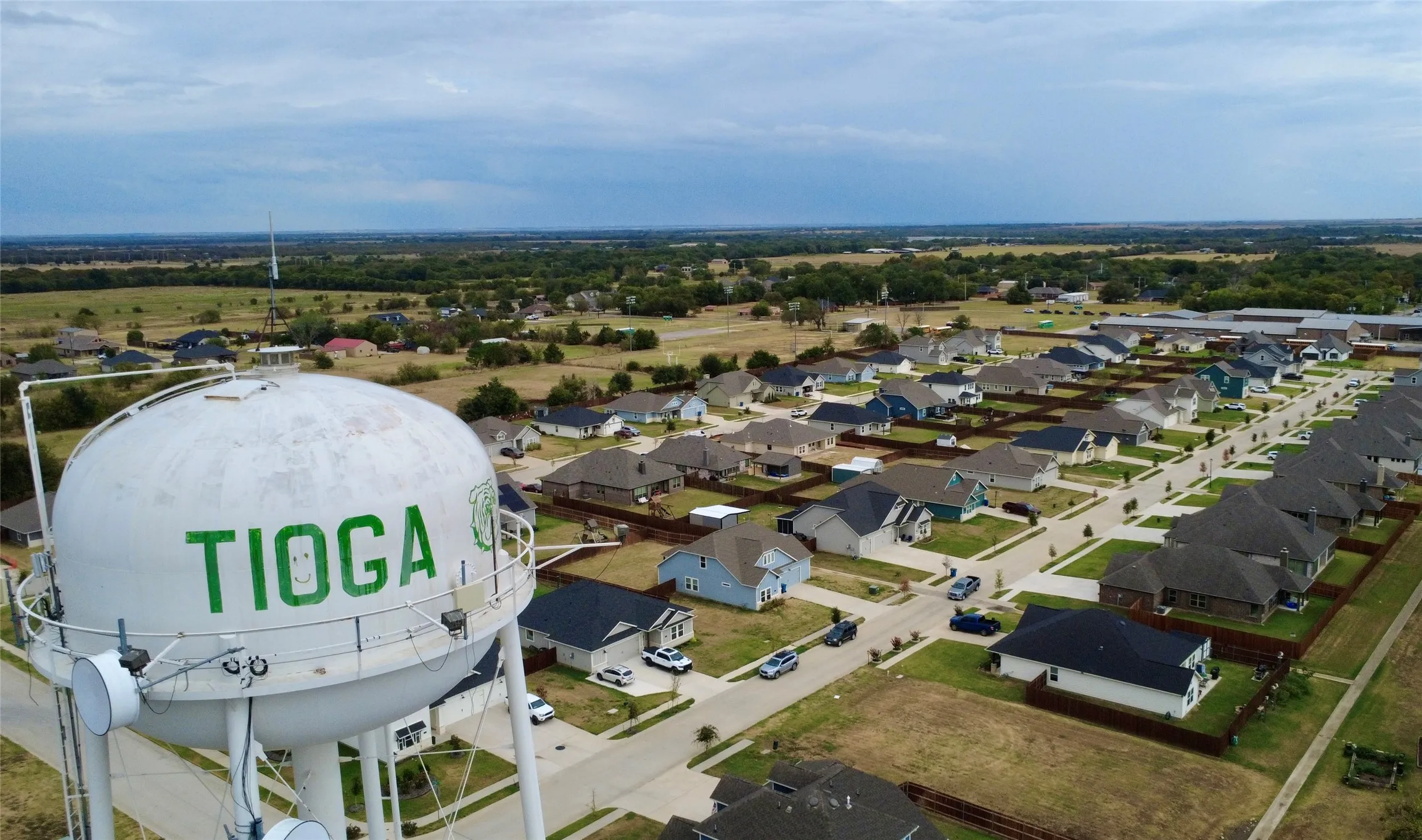 Aerial perspective of a developed residential neighborhood with a water tower displaying "TIOGA"