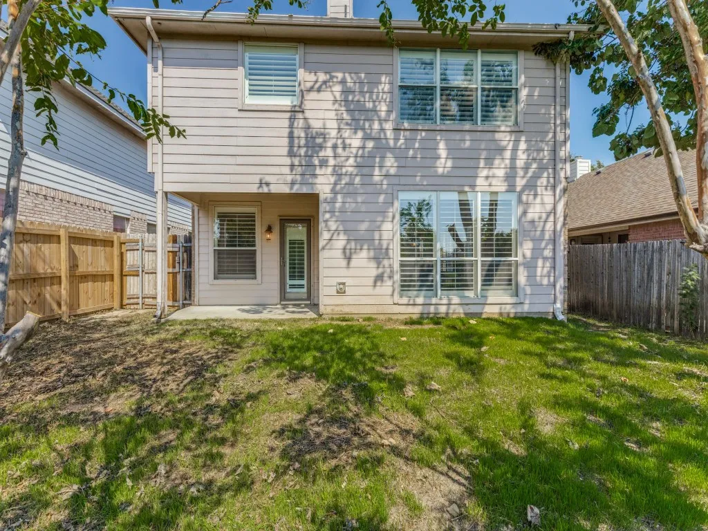 Rear exterior with horizontal siding, multiple windows with blinds, and a ground-level patio