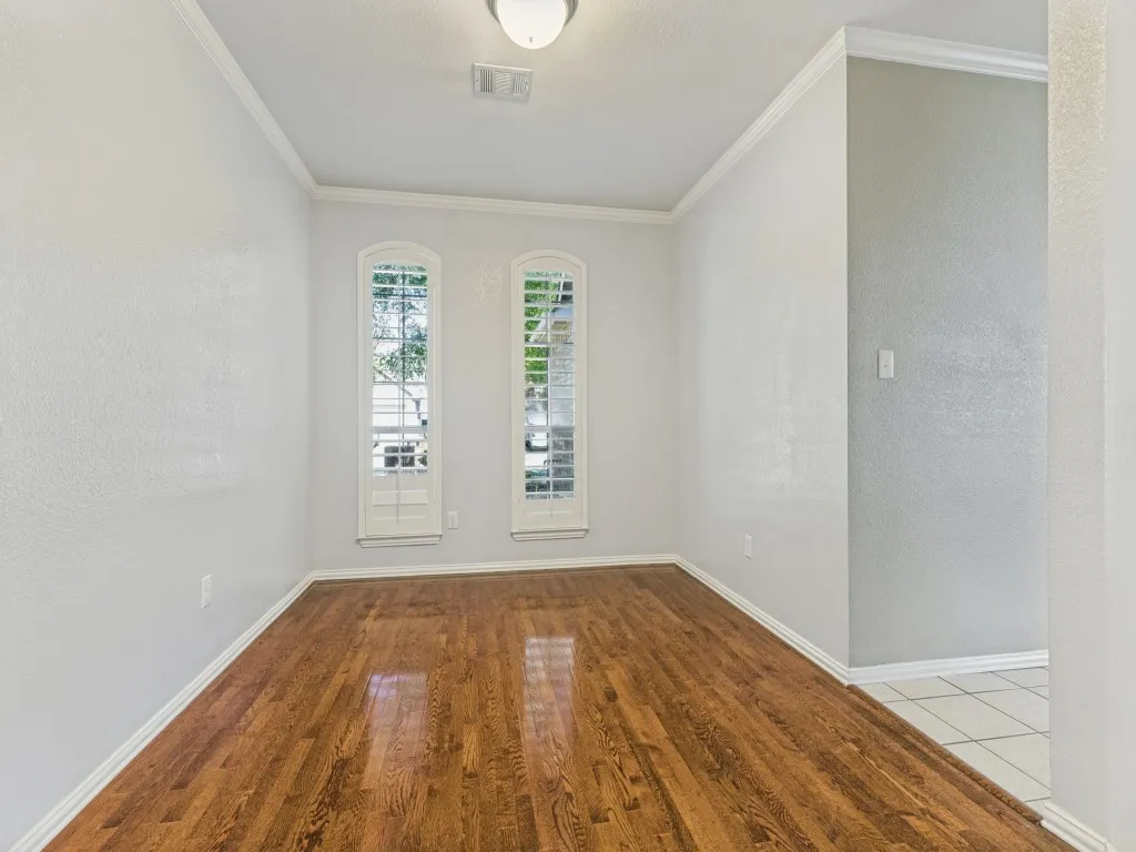 Wood-finish flooring with crown molding and white trim