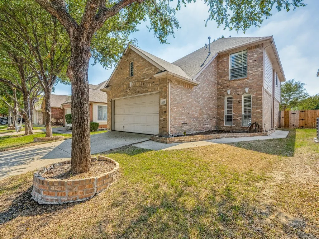 Brick-clad exterior with an attached garage, arched window accents, and a fenced side yard